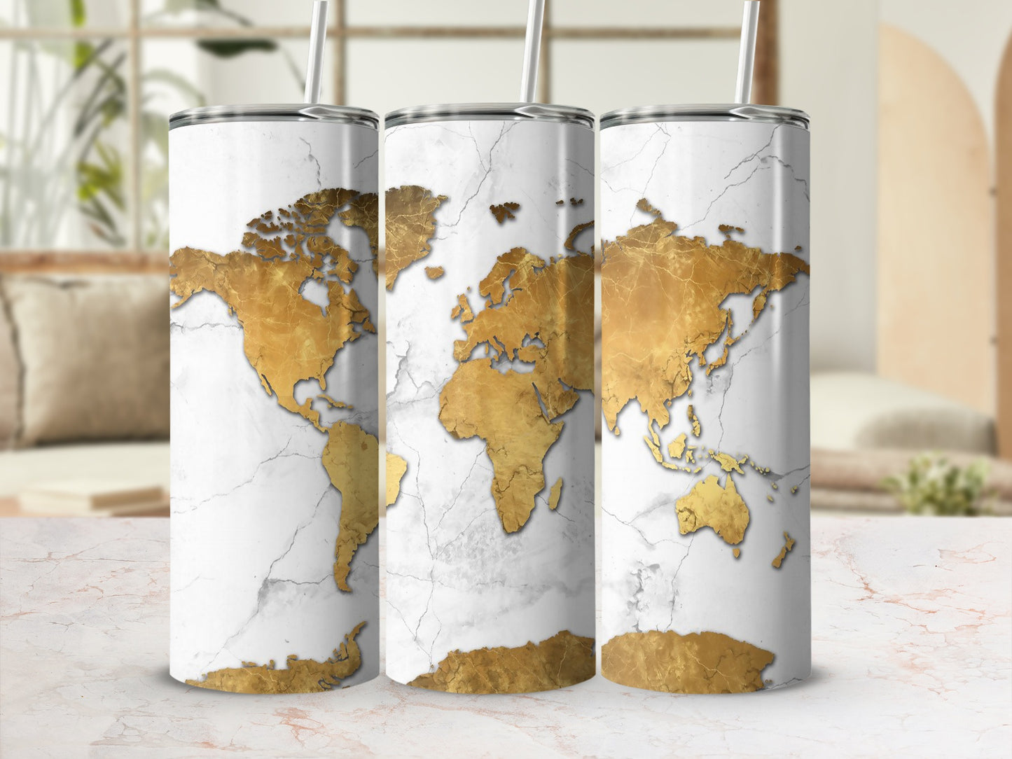 Three tumblers with a gold world map design on a cracked white marble background.