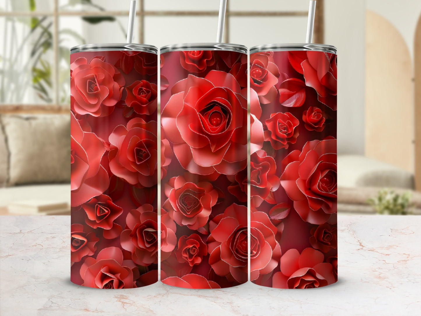 Three red rose-patterned tumblers with straws on a marbled surface.