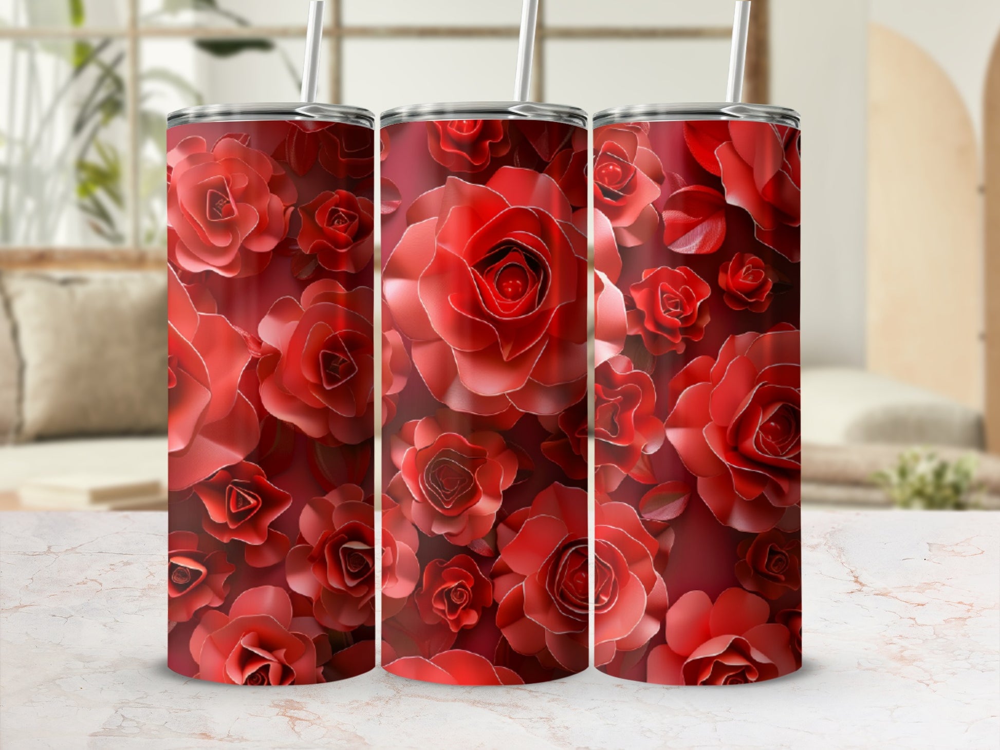 Three red rose-patterned tumblers with straws on a marbled surface.