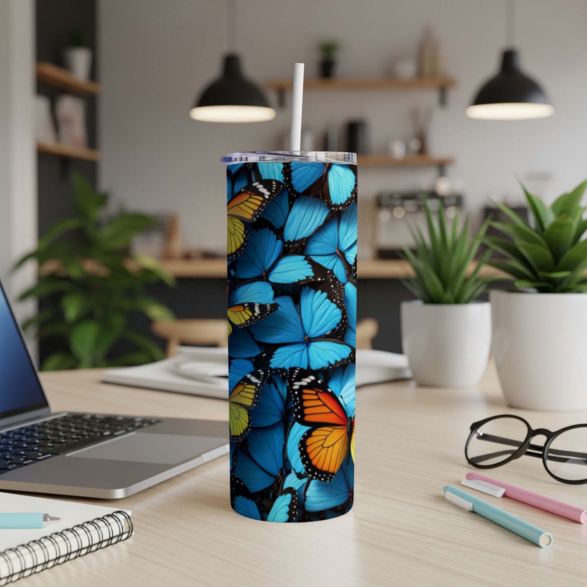 Tumbler with blue and orange butterfly pattern on a desk.