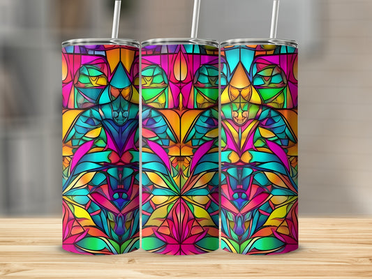 Three colorful stained glass tumblers with straw on a wooden surface.