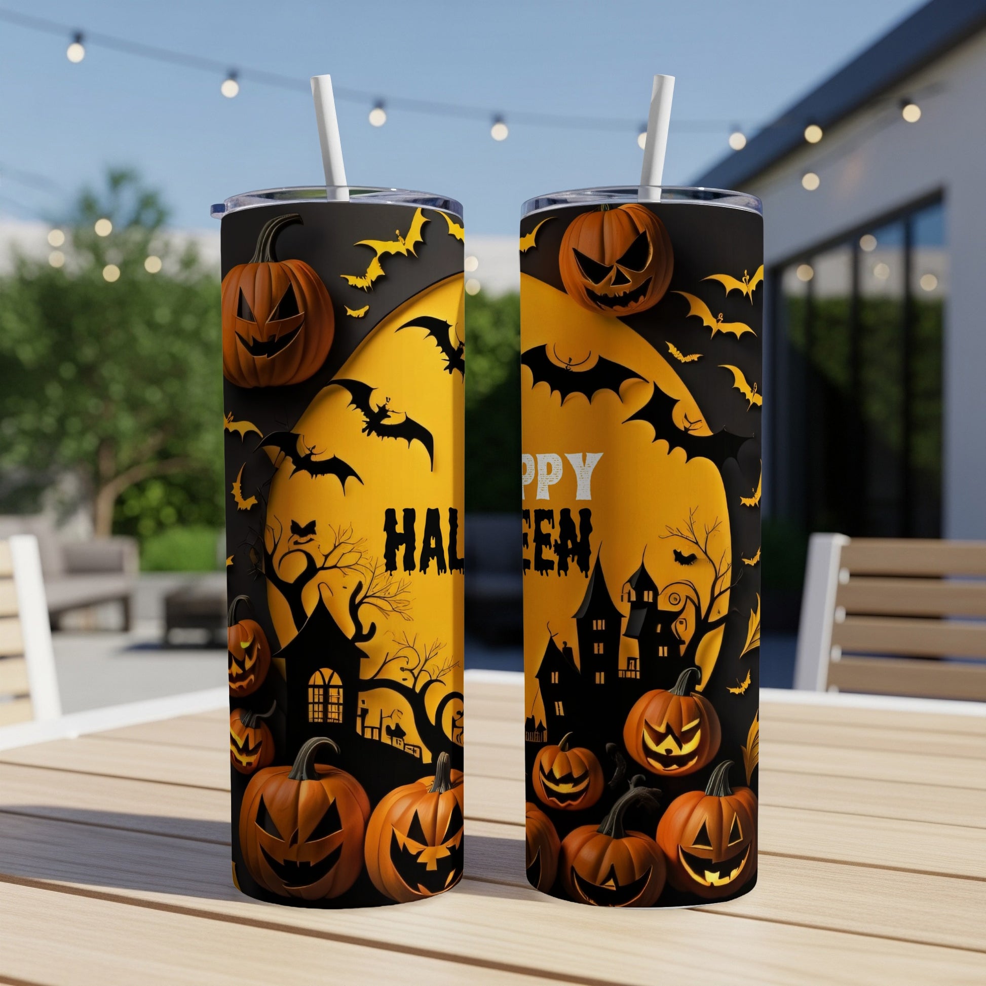 Two Halloween-themed tumblers with pumpkins, bats, and haunted houses on an outdoor table.