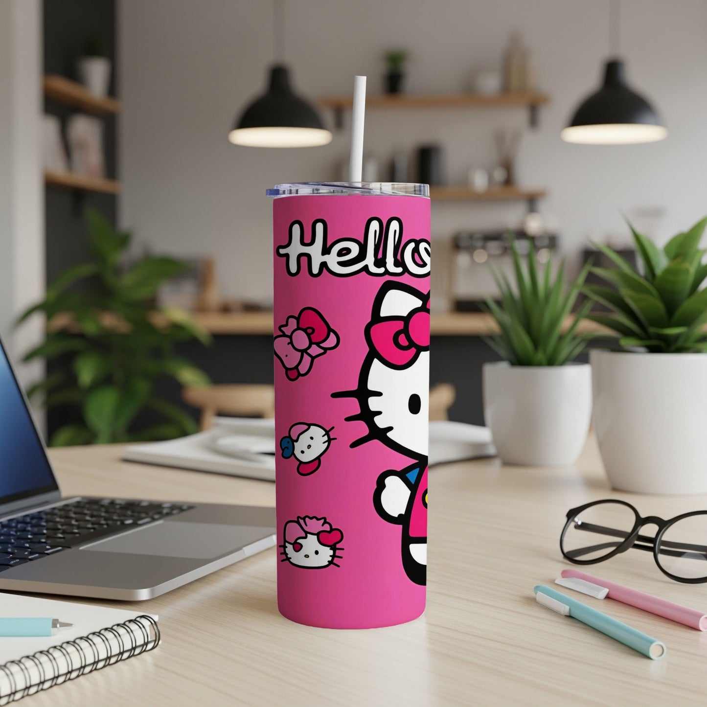 Pink Hello Kitty tumbler with straw, laptop, and pens on desk.
