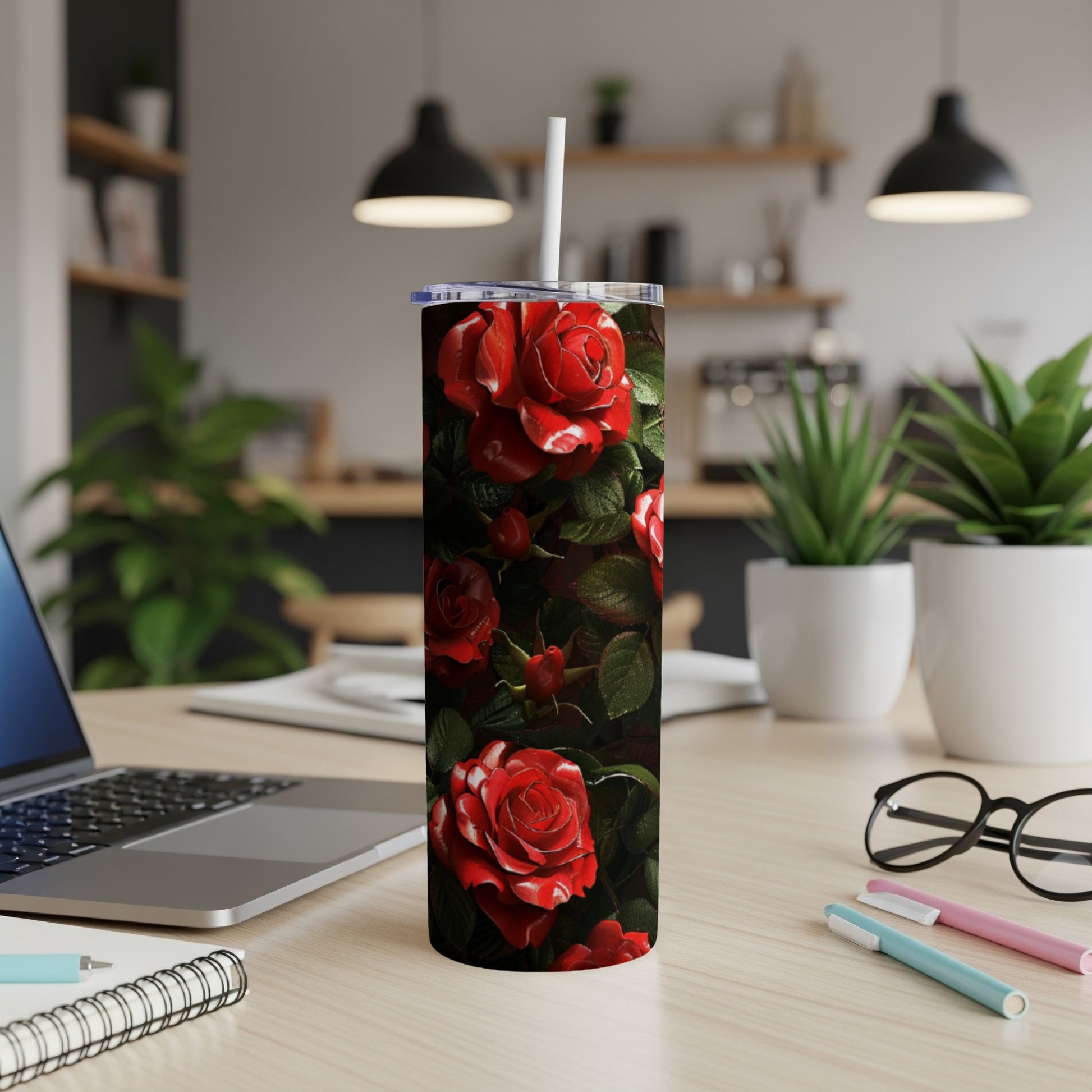 Red roses with white edges wrap around a white tumbler on a desk.