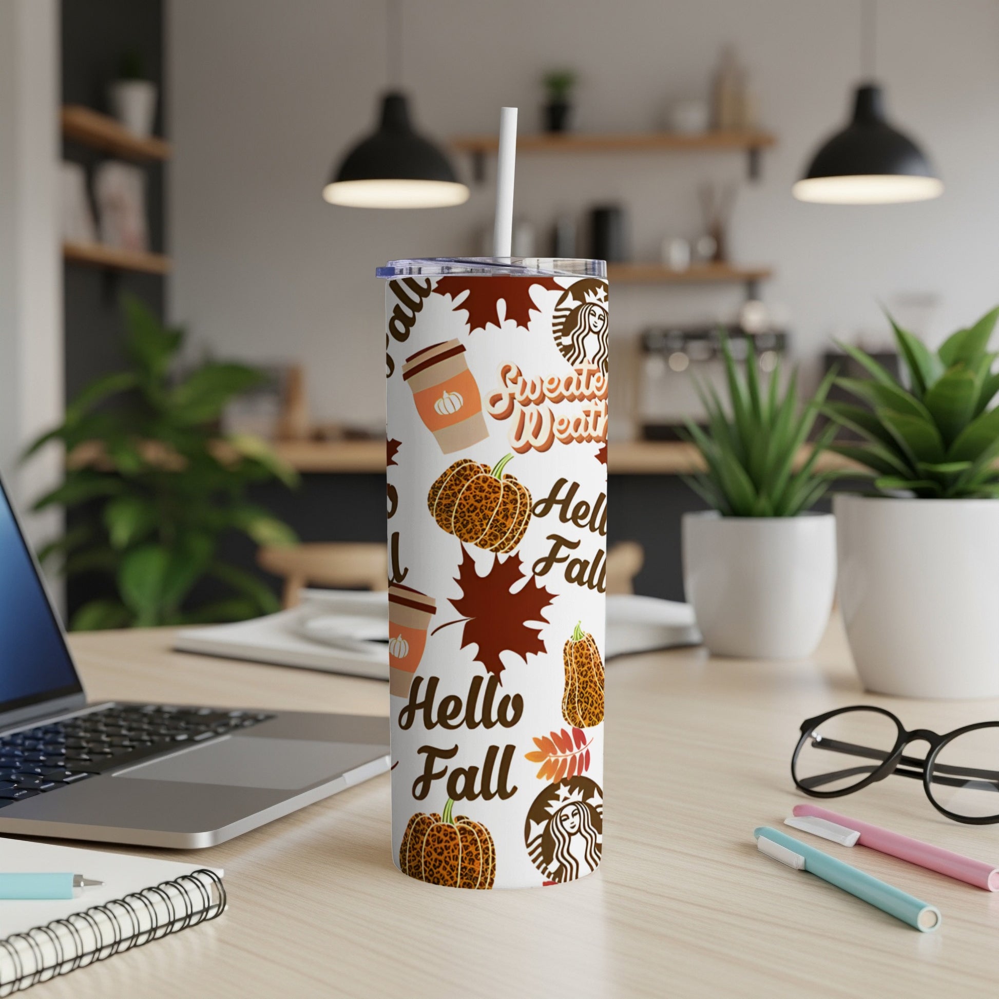 White tumbler with "Hello Fall" and pumpkin patterns on a desk.
