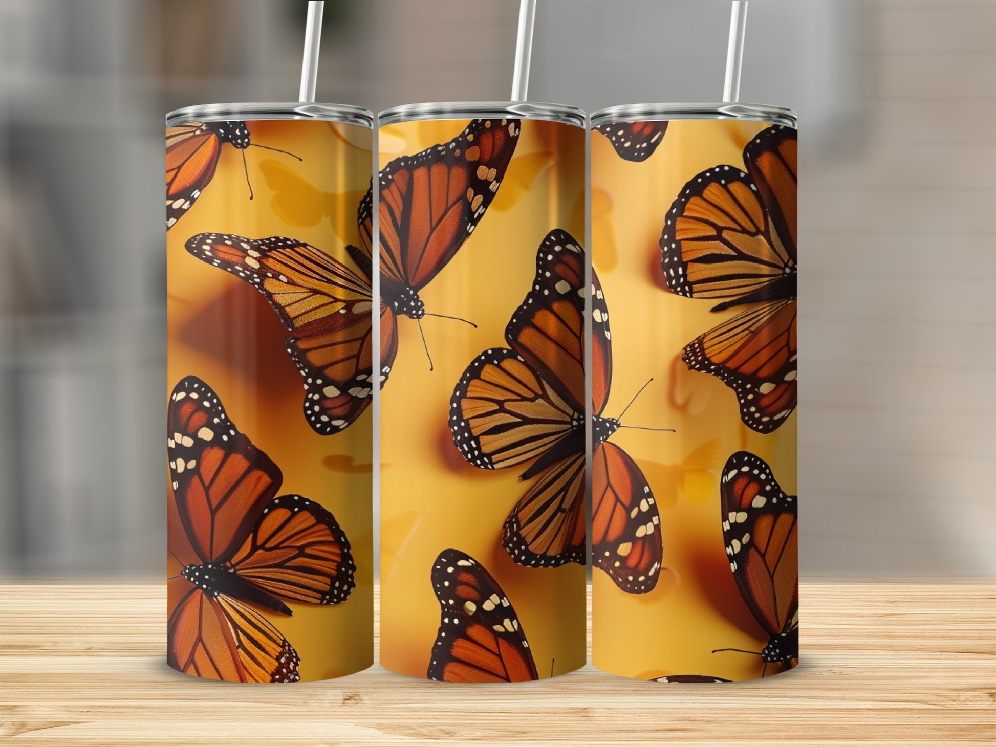 Three tumblers with orange and black monarch butterflies on a yellow background.