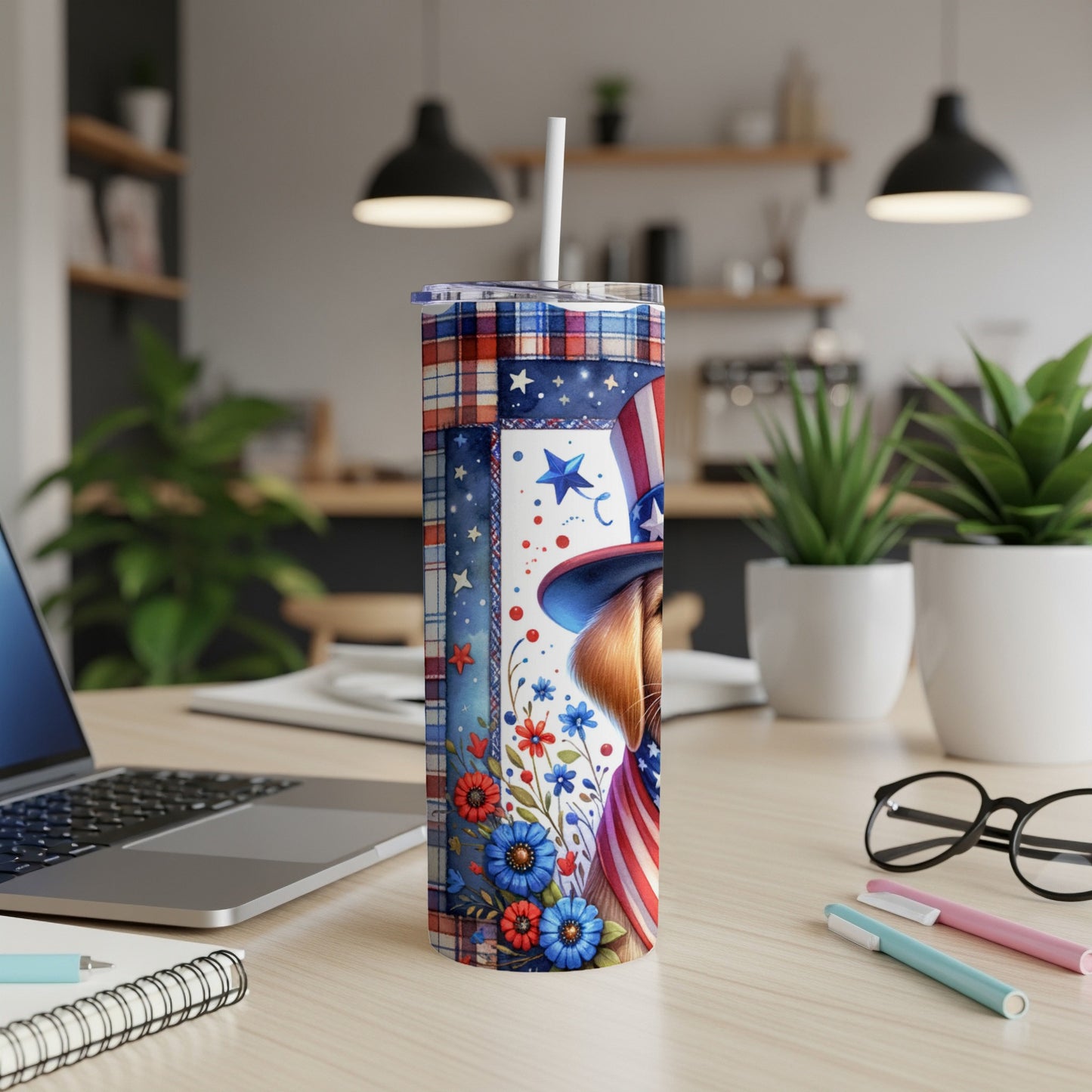 Patriotic tumbler with stars, stripes, and floral design on a desk.