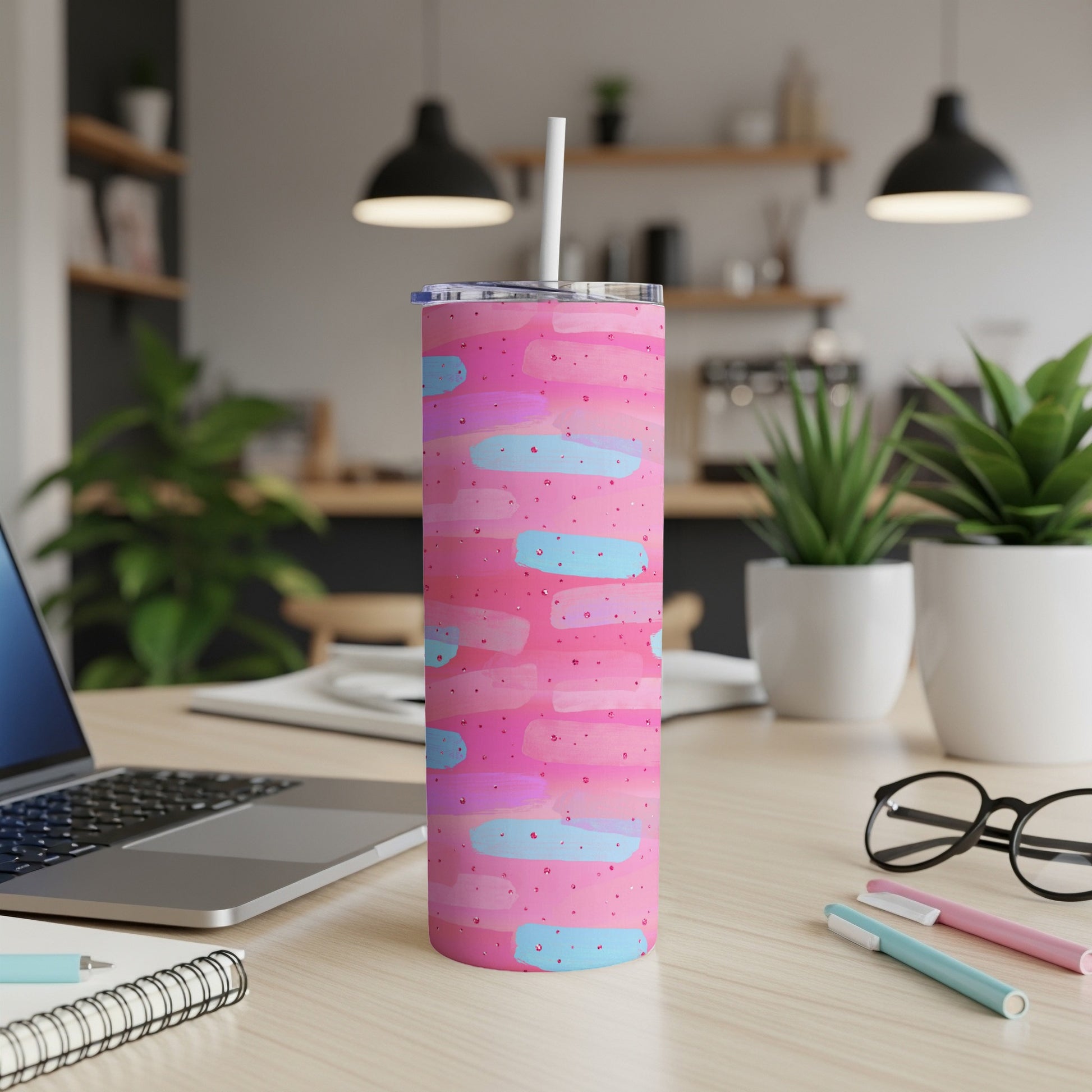Pink tumbler with blue and purple paint strokes and dots, with straw.