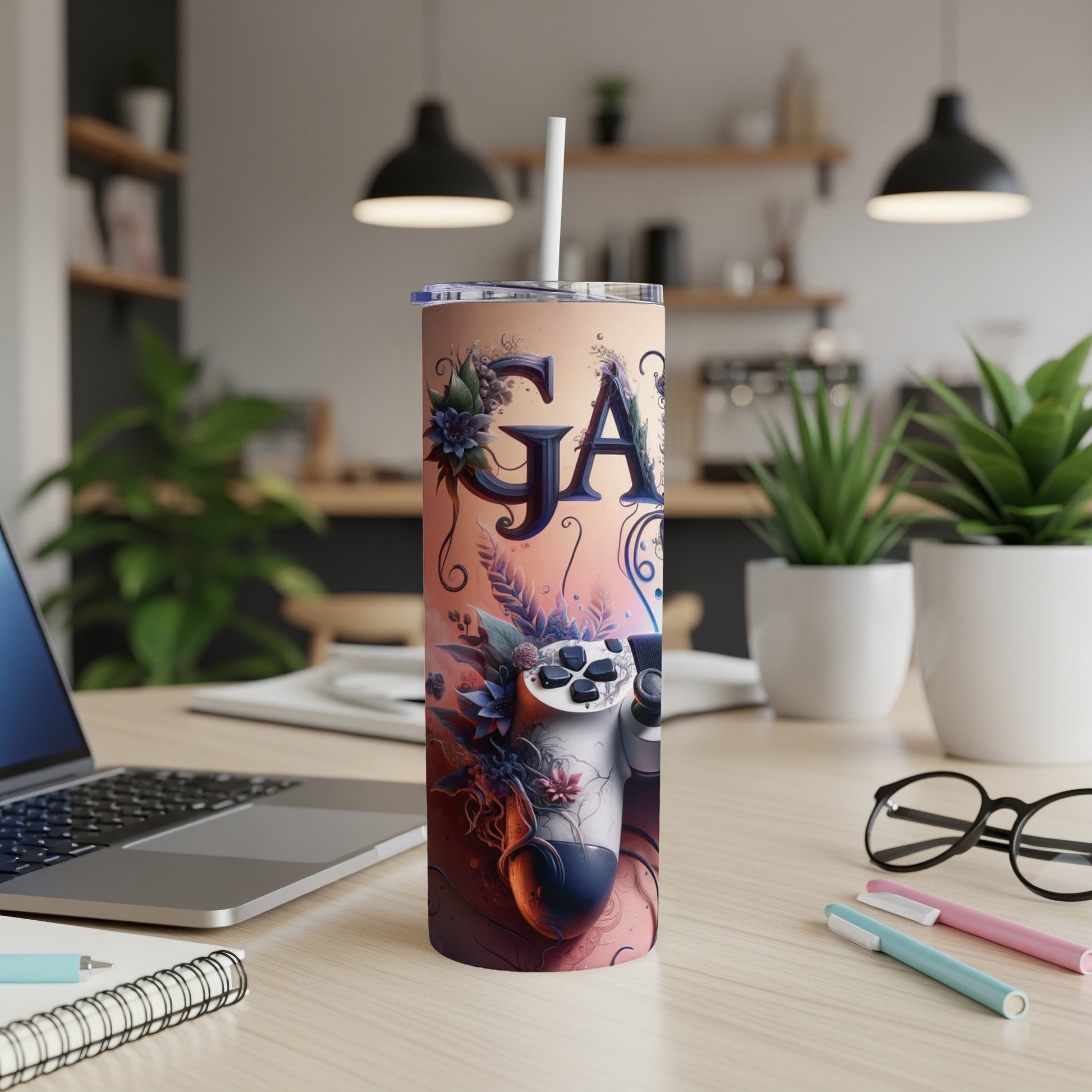 Tumbler with "GA" and gaming controller design, on a desk with laptop.