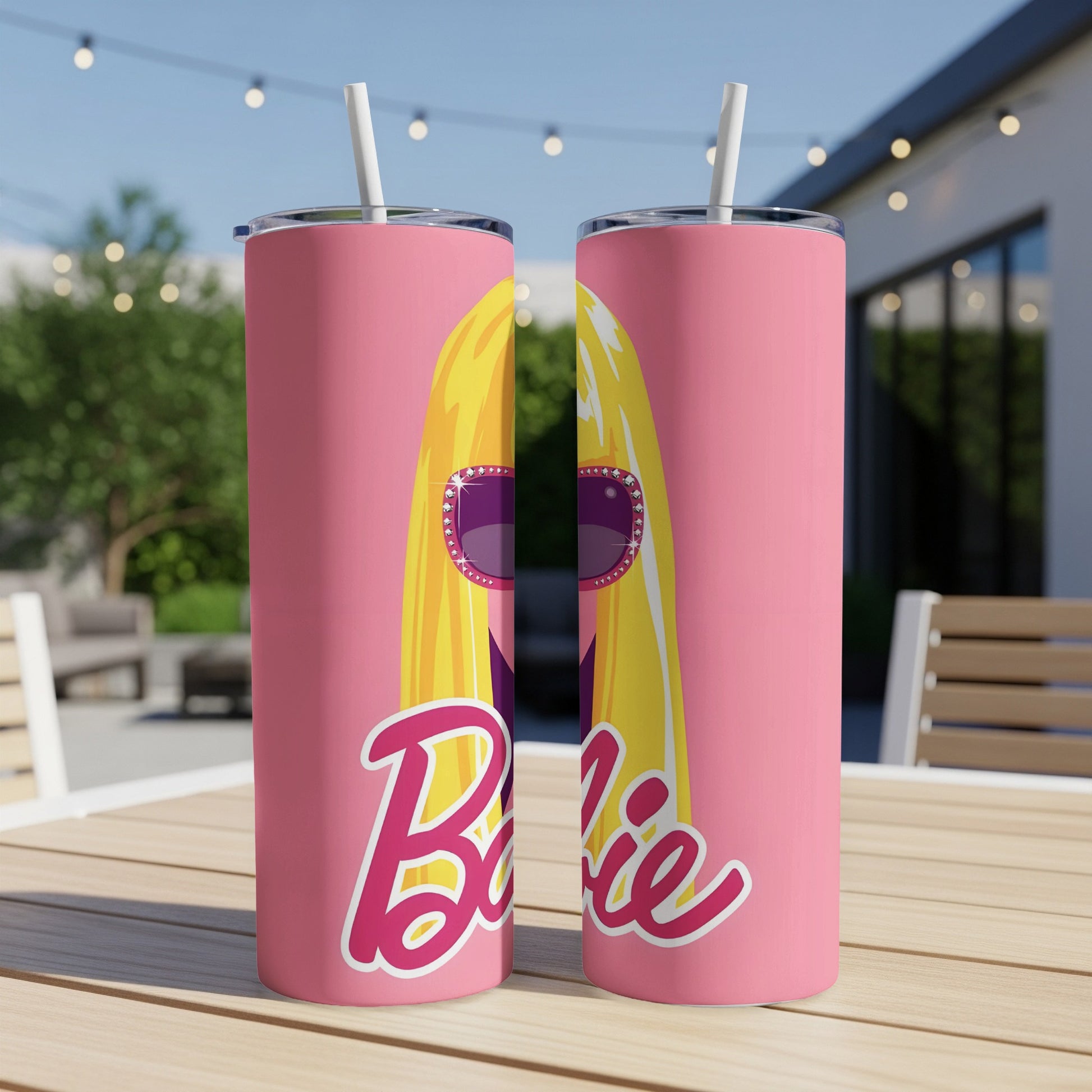 Pink Barbie tumbler with sunglasses and straw on a table.