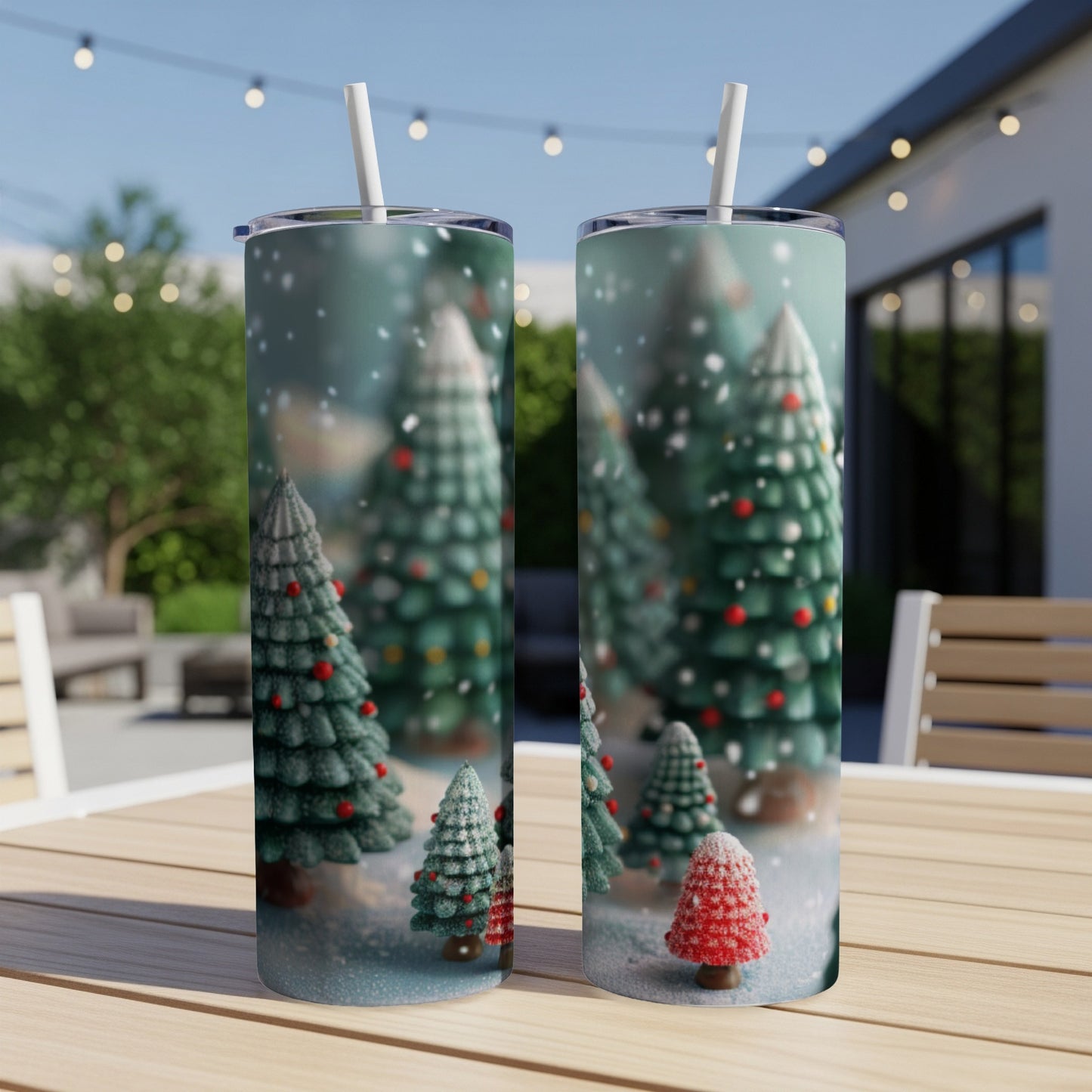 Two tumblers with festive Christmas tree designs sit on a wooden table outdoors.