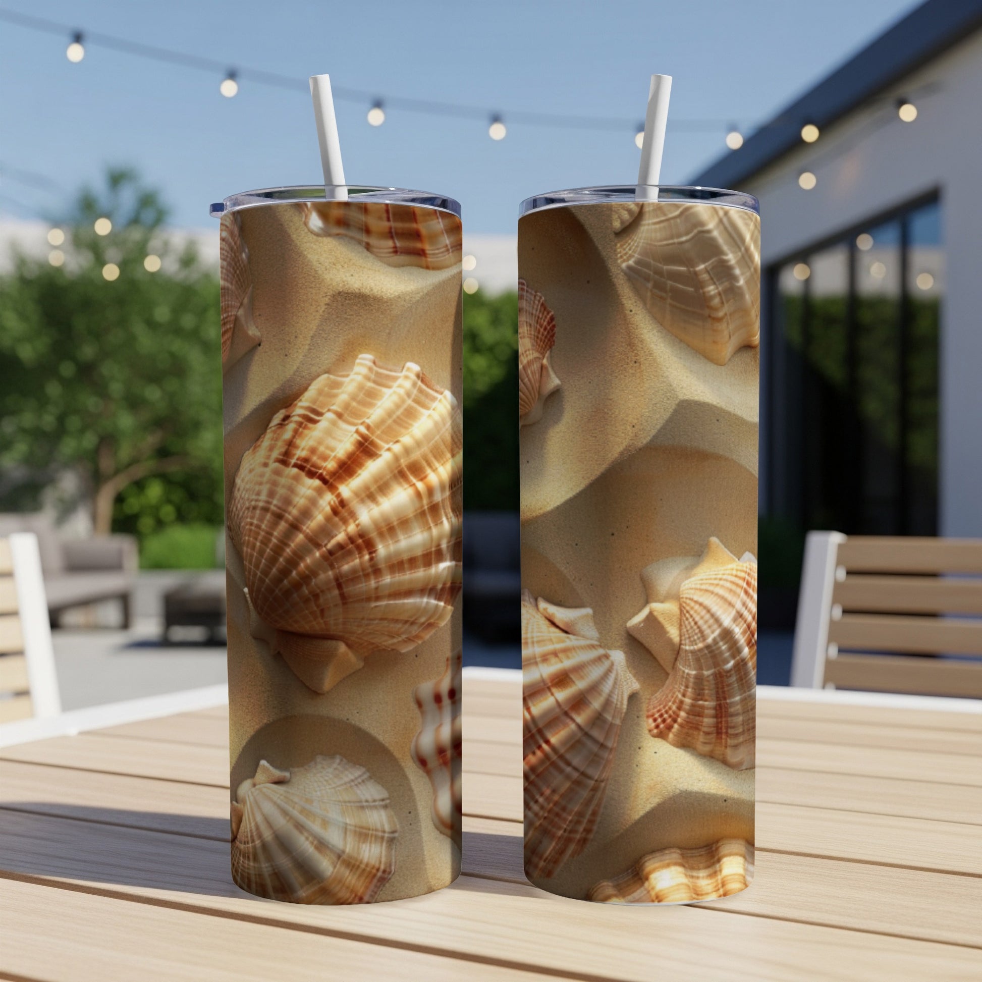 Two tumblers with a seashell and sand pattern on a wooden table outdoors.