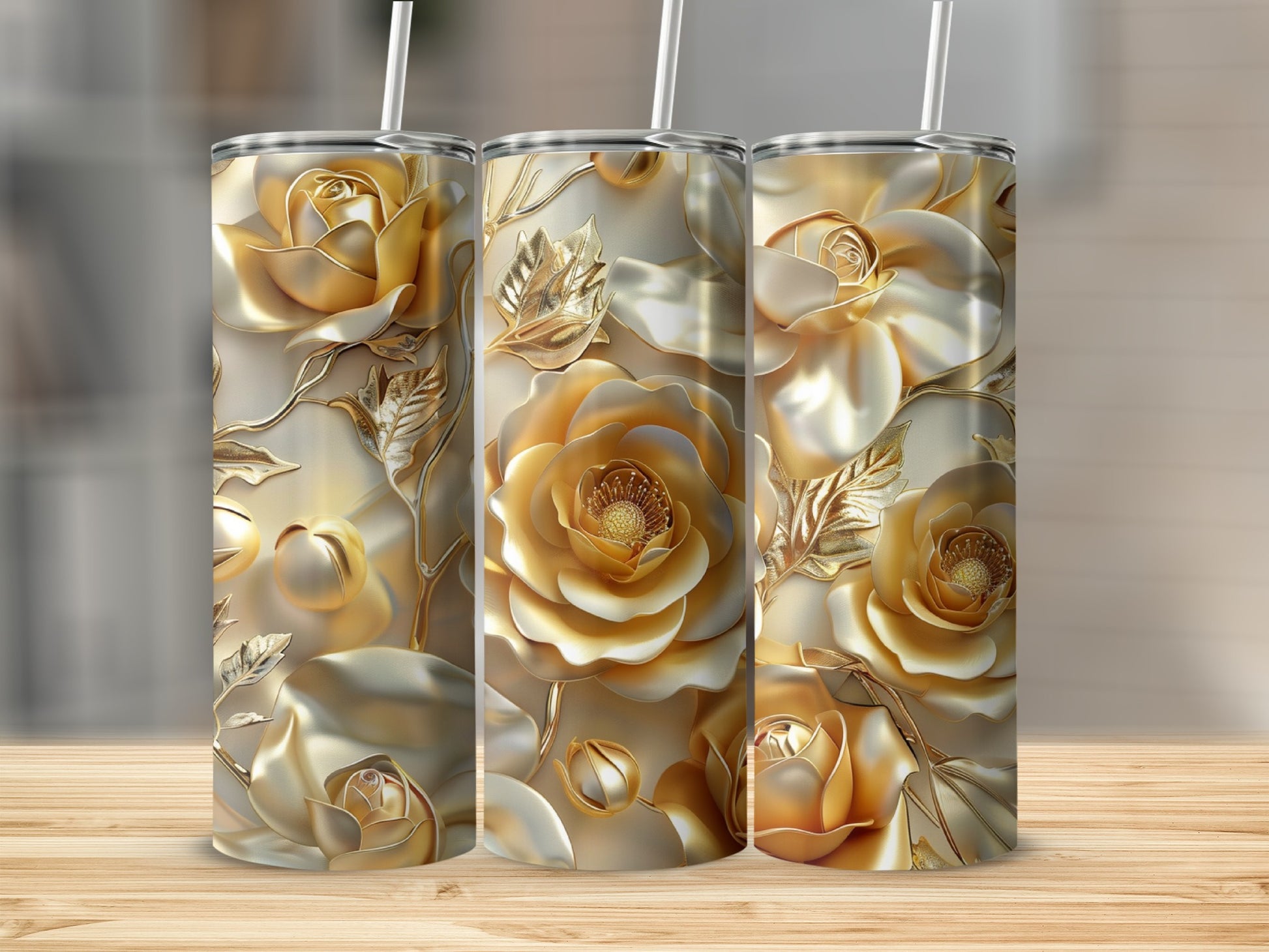 Three gold tumblers with embossed rose and leaf designs on a wooden surface.