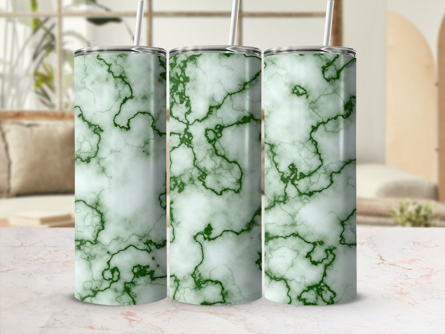 Three green marble pattern tumblers with straws on a marble countertop.