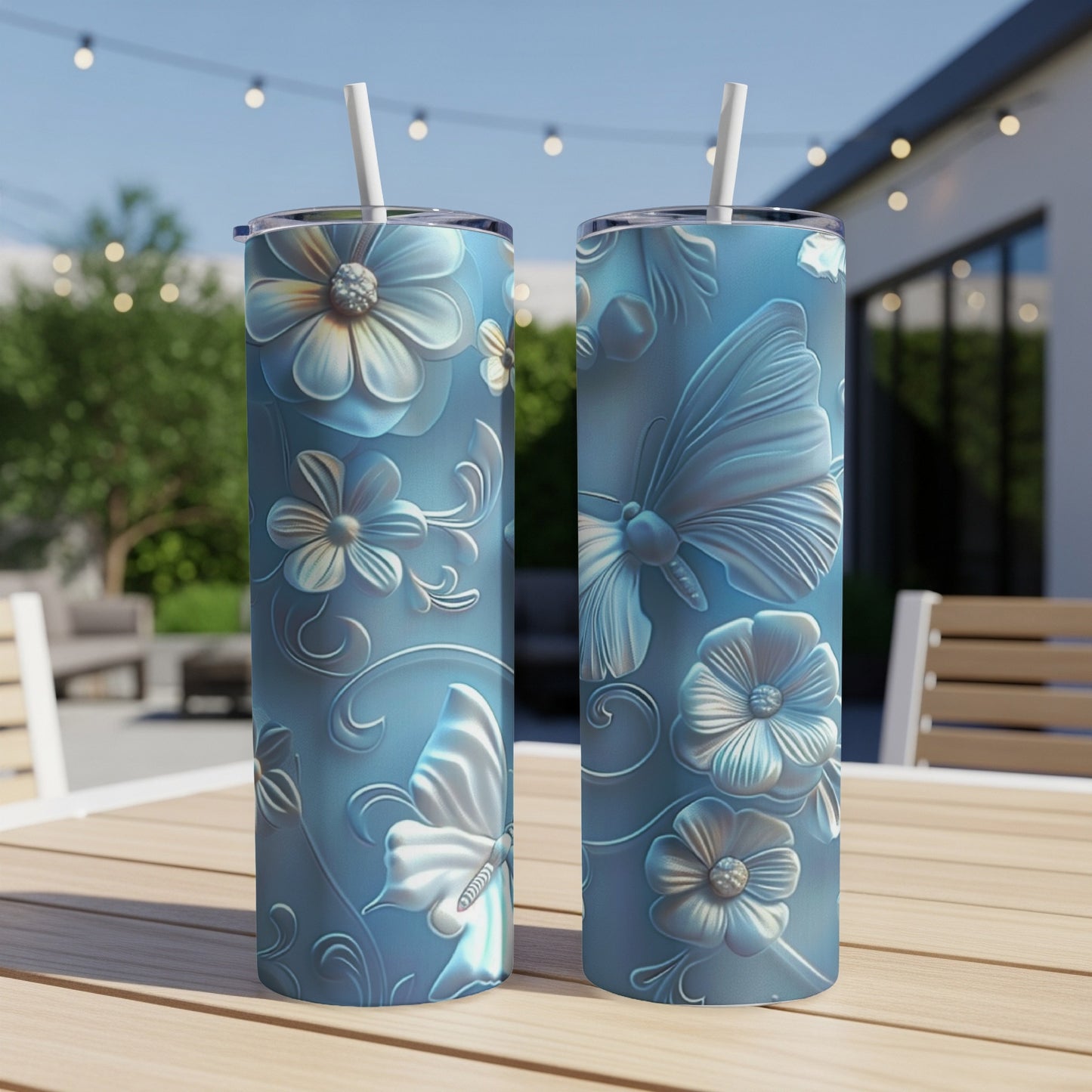 Two blue tumblers with embossed floral and butterfly designs sit on a wooden table.