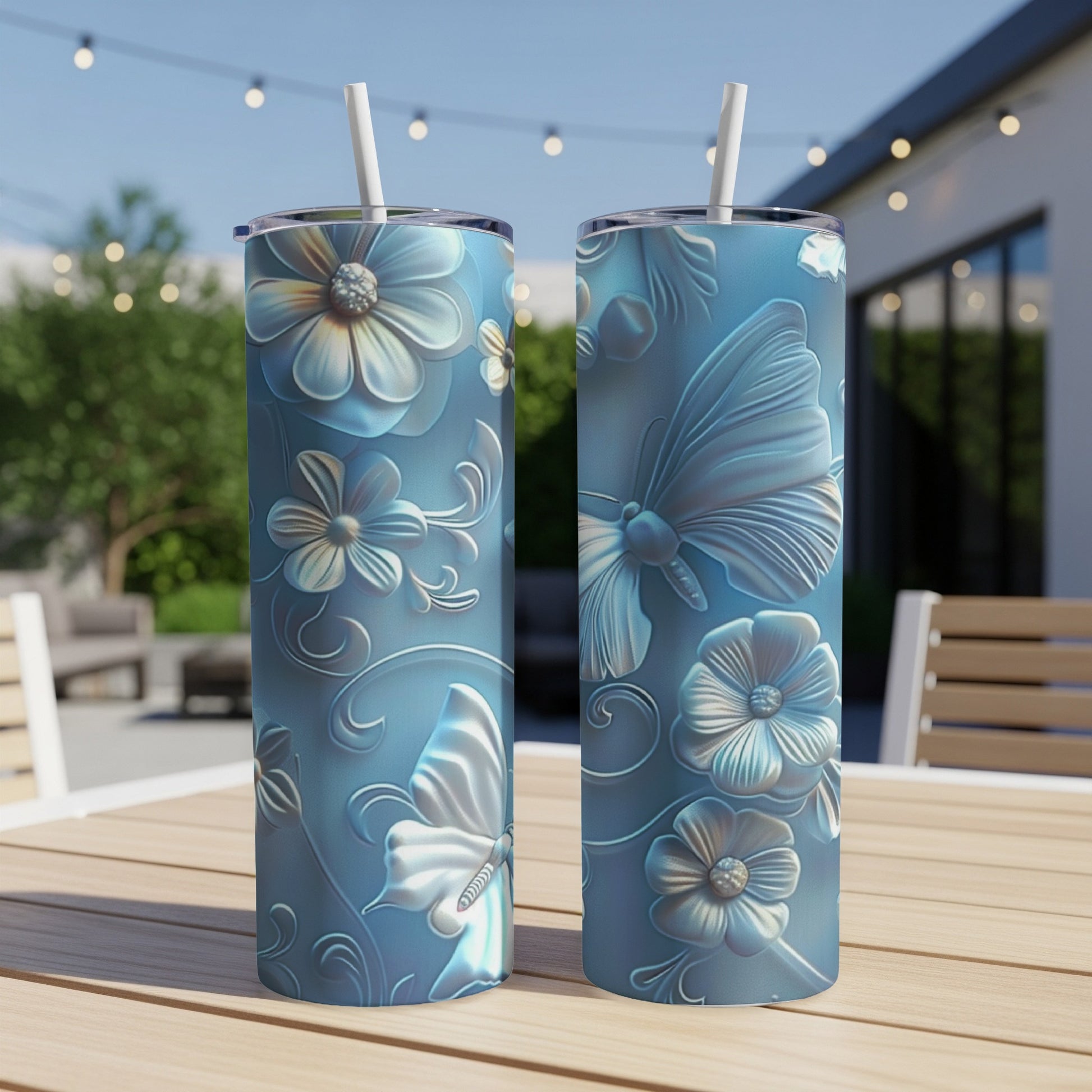 Two blue tumblers with embossed floral and butterfly designs sit on a wooden table.