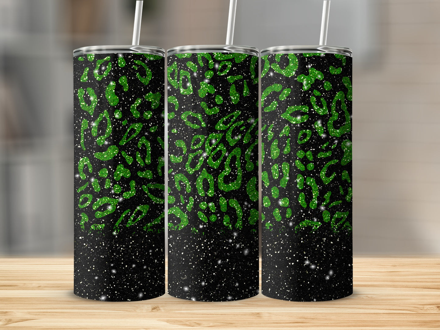 Three glittery green leopard print tumblers with white straws on a wooden surface.