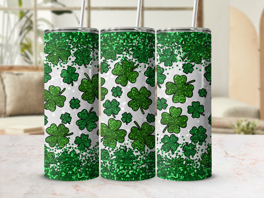 Three tumblers with green glitter and shamrocks on a blurred background.