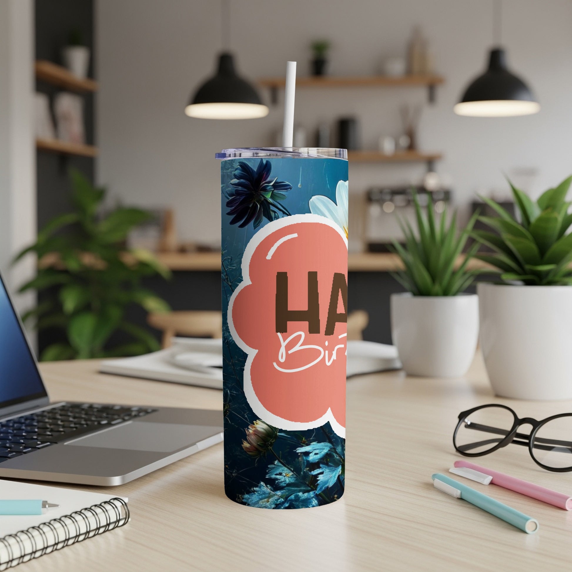 Happy Birthday tumbler with floral design on a desk.
