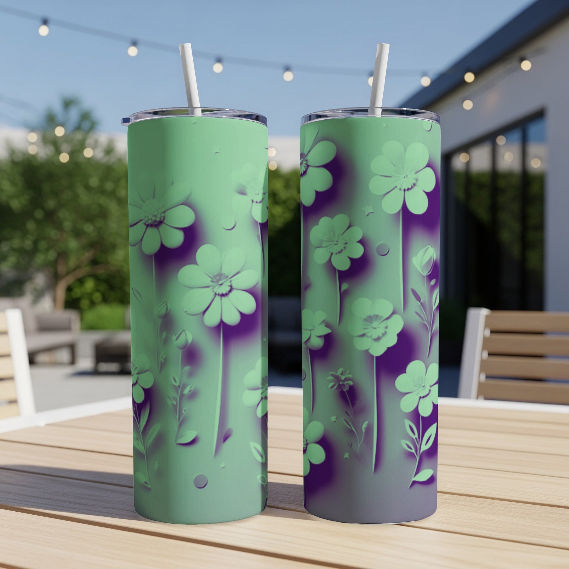 Two mint green tumblers with purple floral design on a table outdoors.