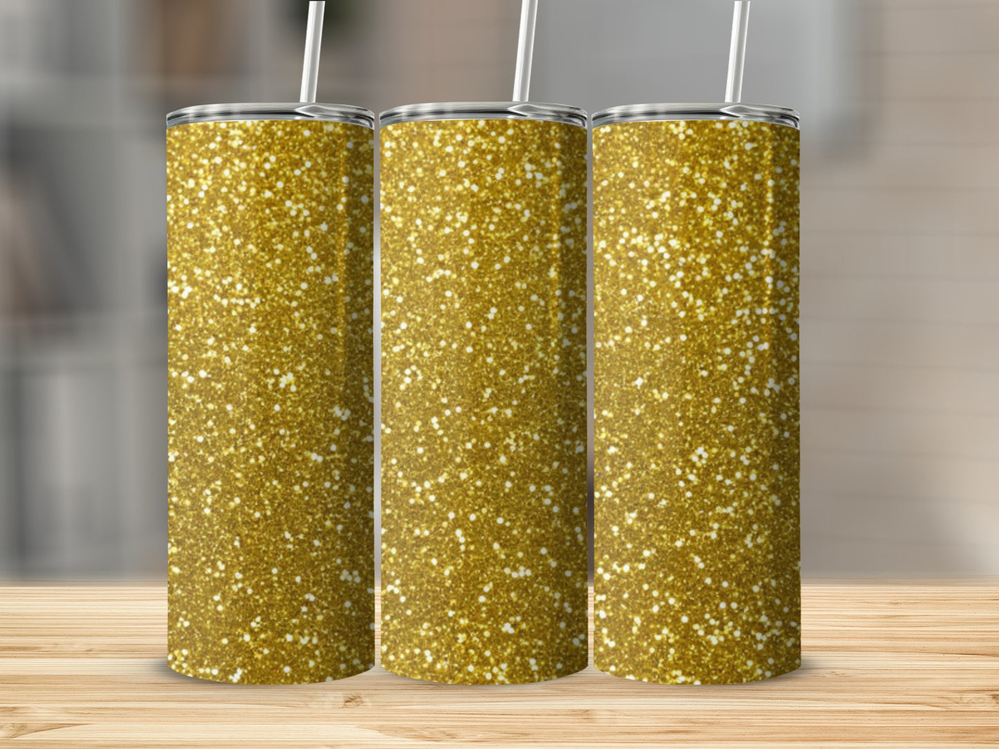 Three gold glitter tumblers with straws on a wooden surface.