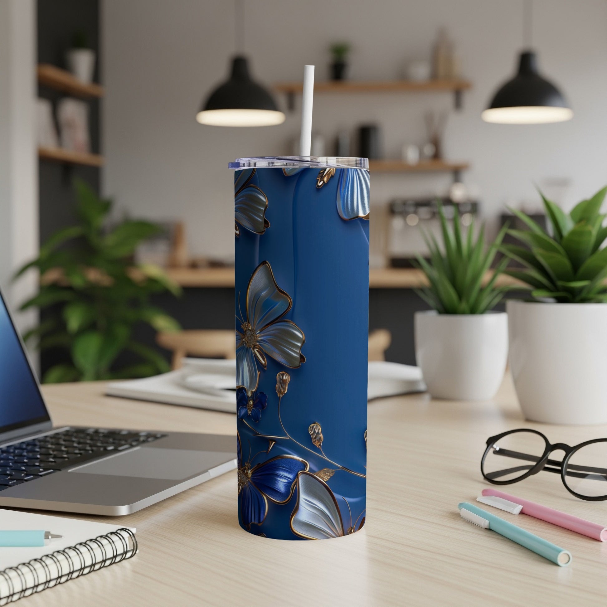 Blue tumbler with gold floral accents on a wooden desk.