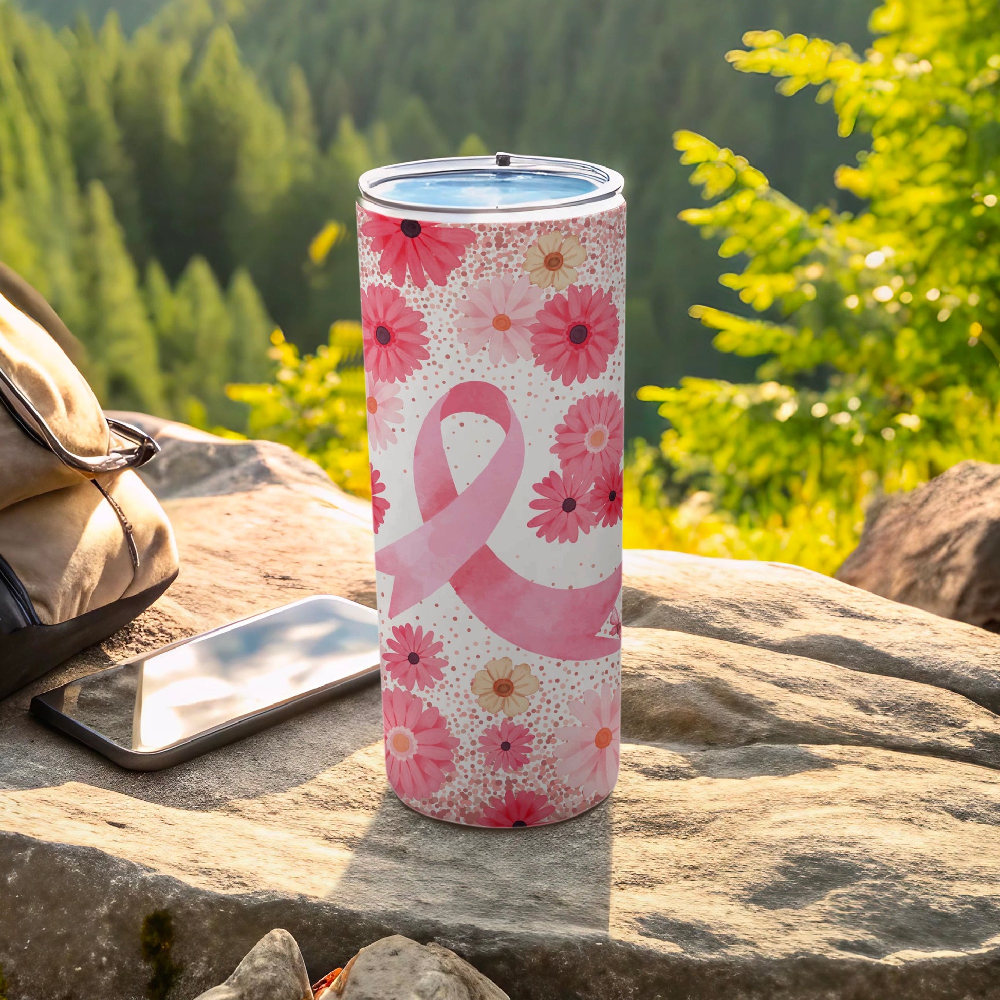 Pink ribbon and floral design on a tall tumbler with phone and backpack.