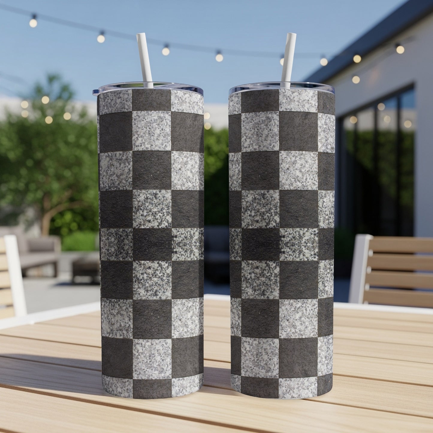 Two tall tumblers with a black and white checkerboard pattern, with straws.