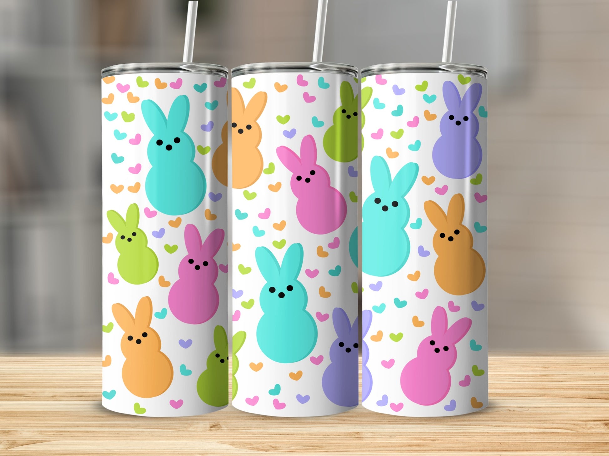 Three tumblers with bunny and heart pattern on wooden surface.