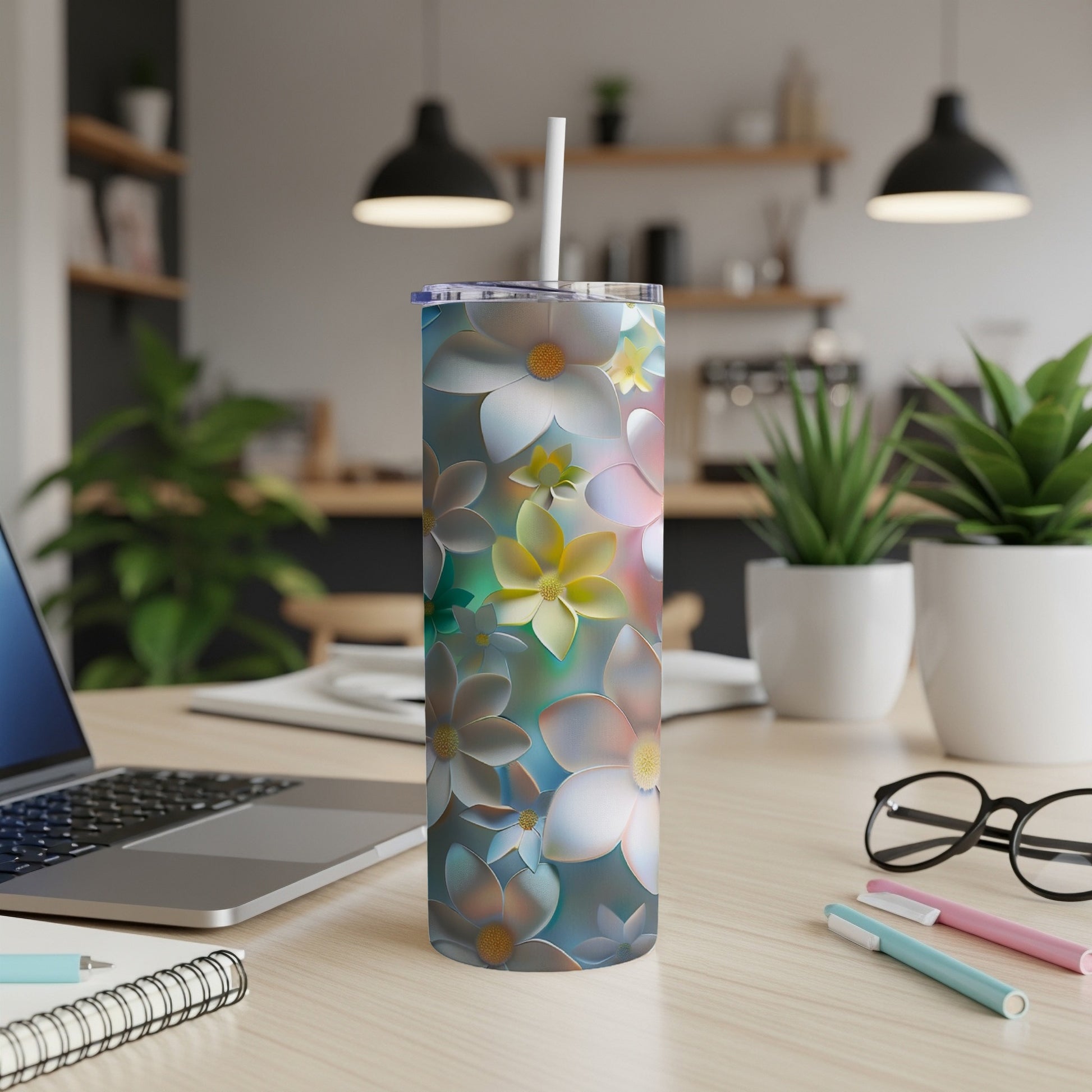 Floral patterned skinny tumbler with straw on a desk.