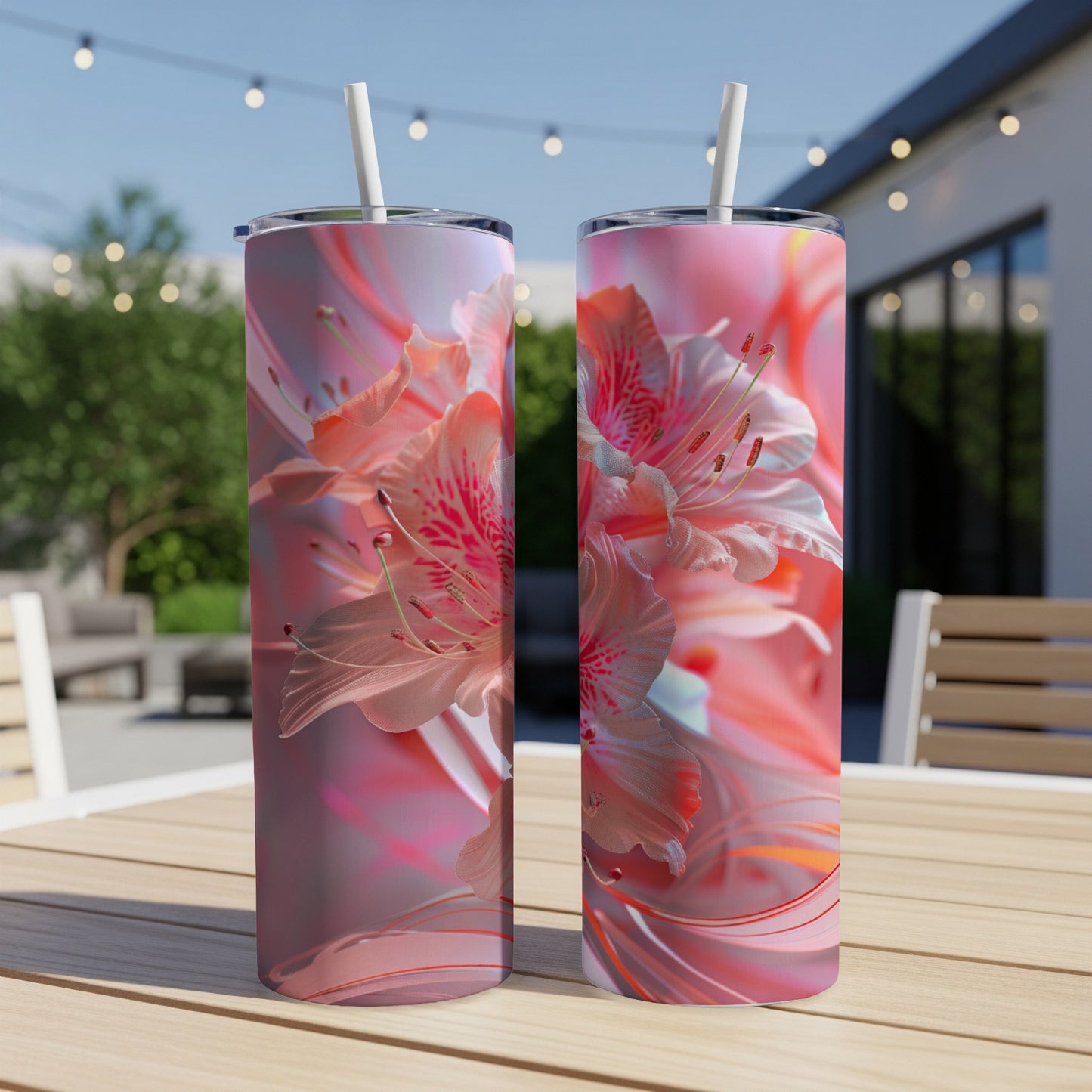 Two pink floral patterned tumblers with straws on a wooden table outdoors.