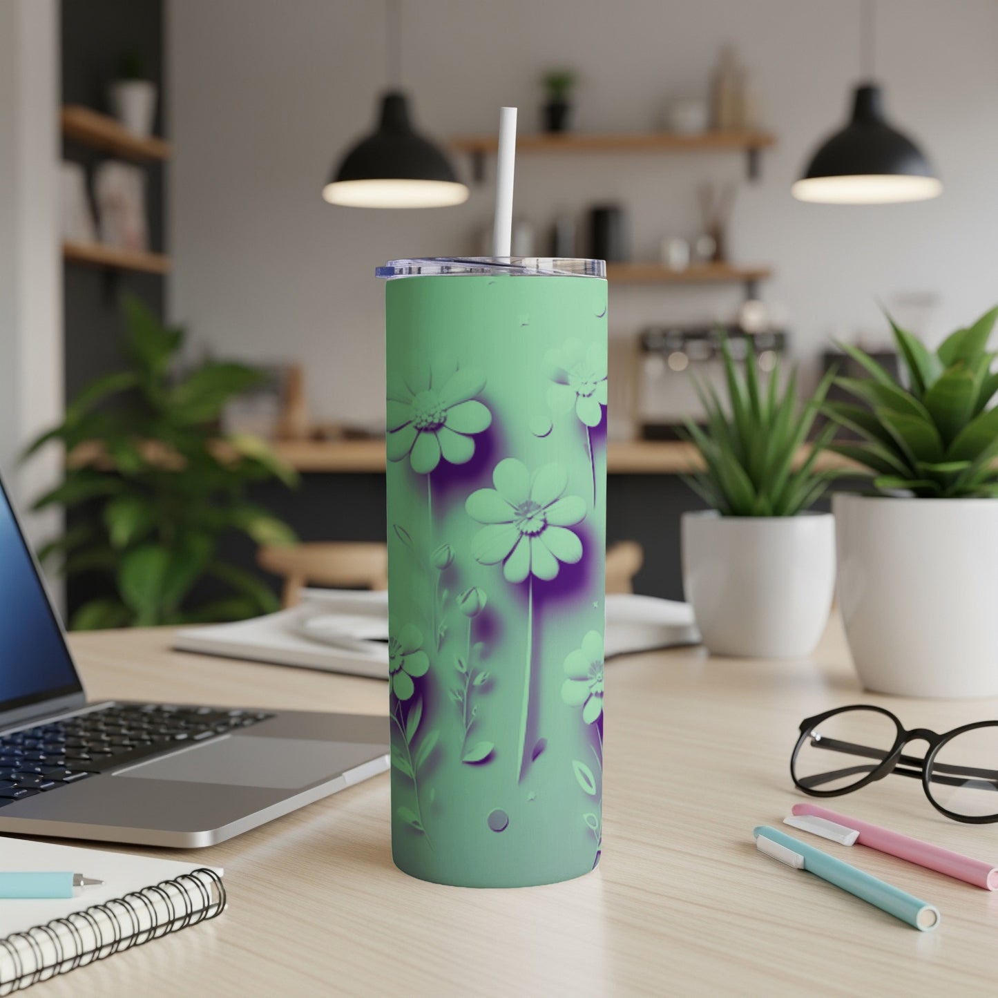 Green tumbler with purple floral pattern and straw on a desk.