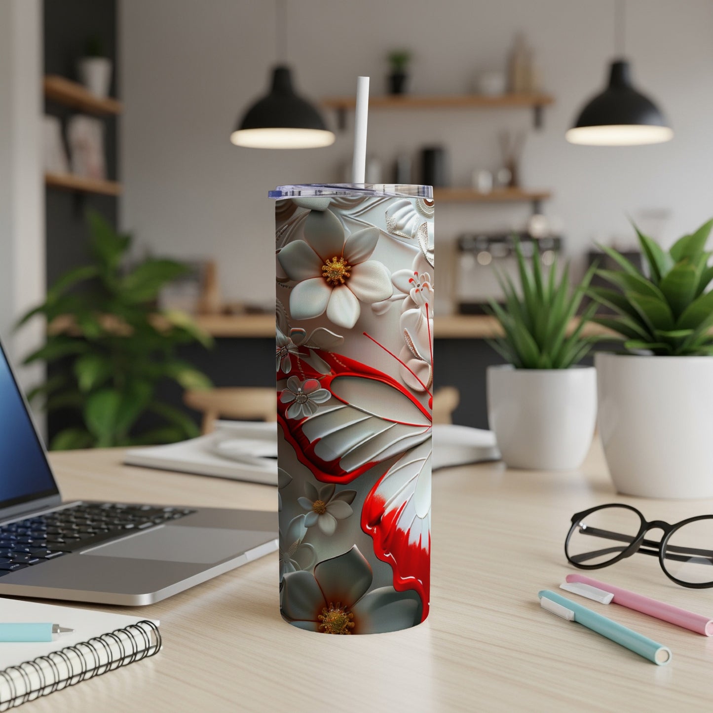 White tumbler with red butterfly and floral pattern, on desk.