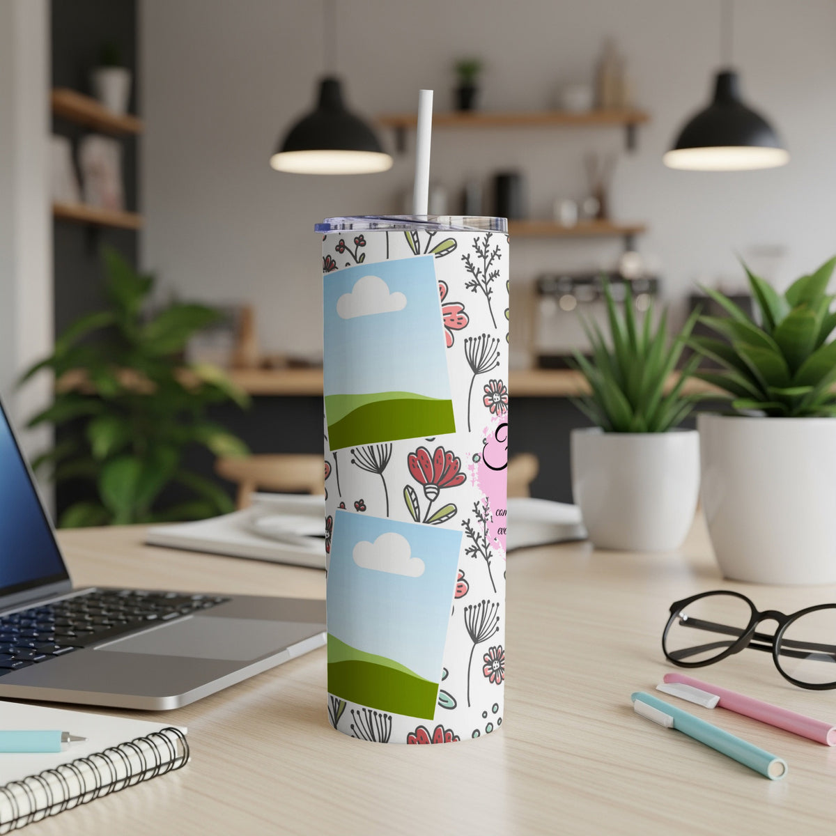 Floral tumbler with landscape photos, pink text, and straw on a desk.