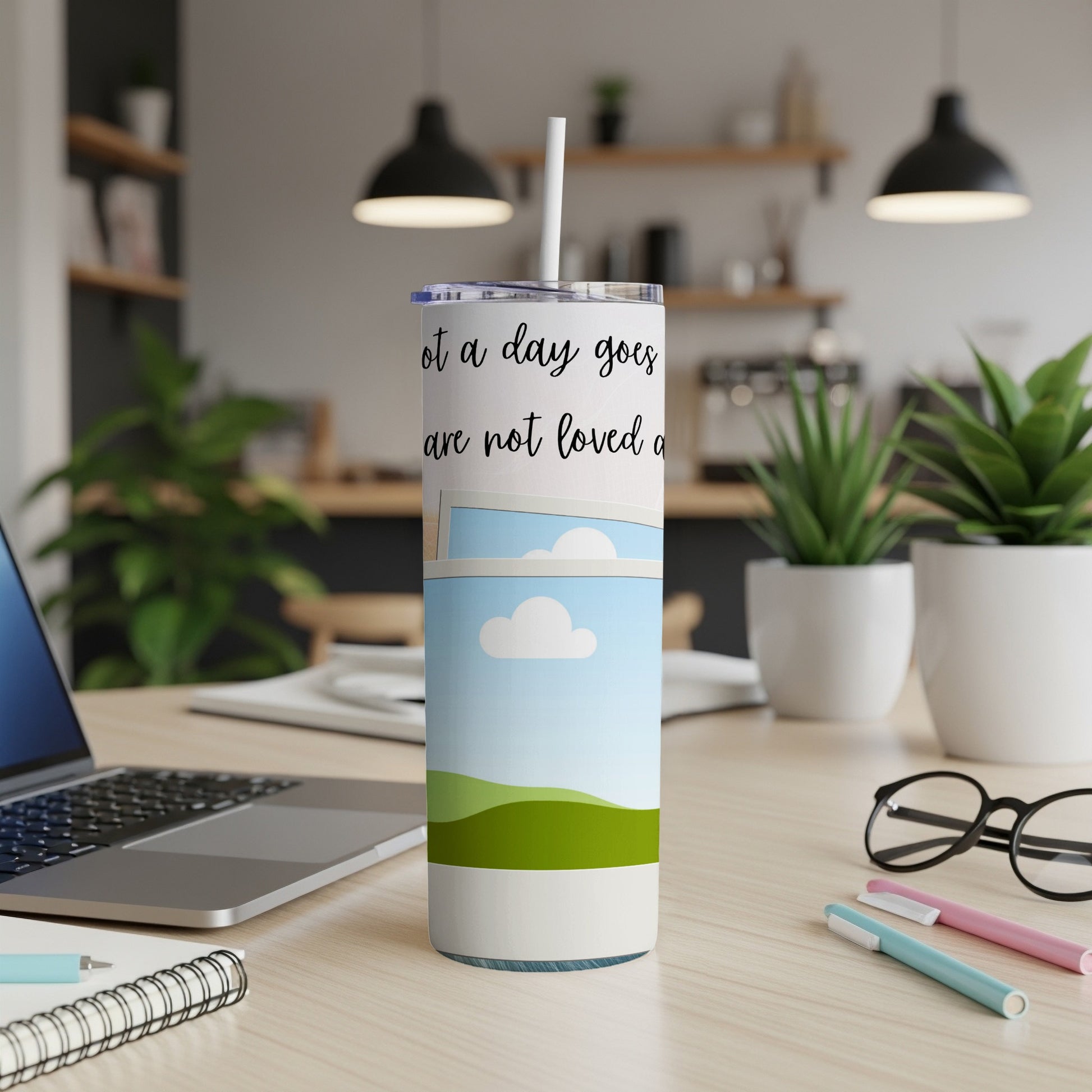 White tumbler with text "Not a day goes are not loved a" and a sky scene.