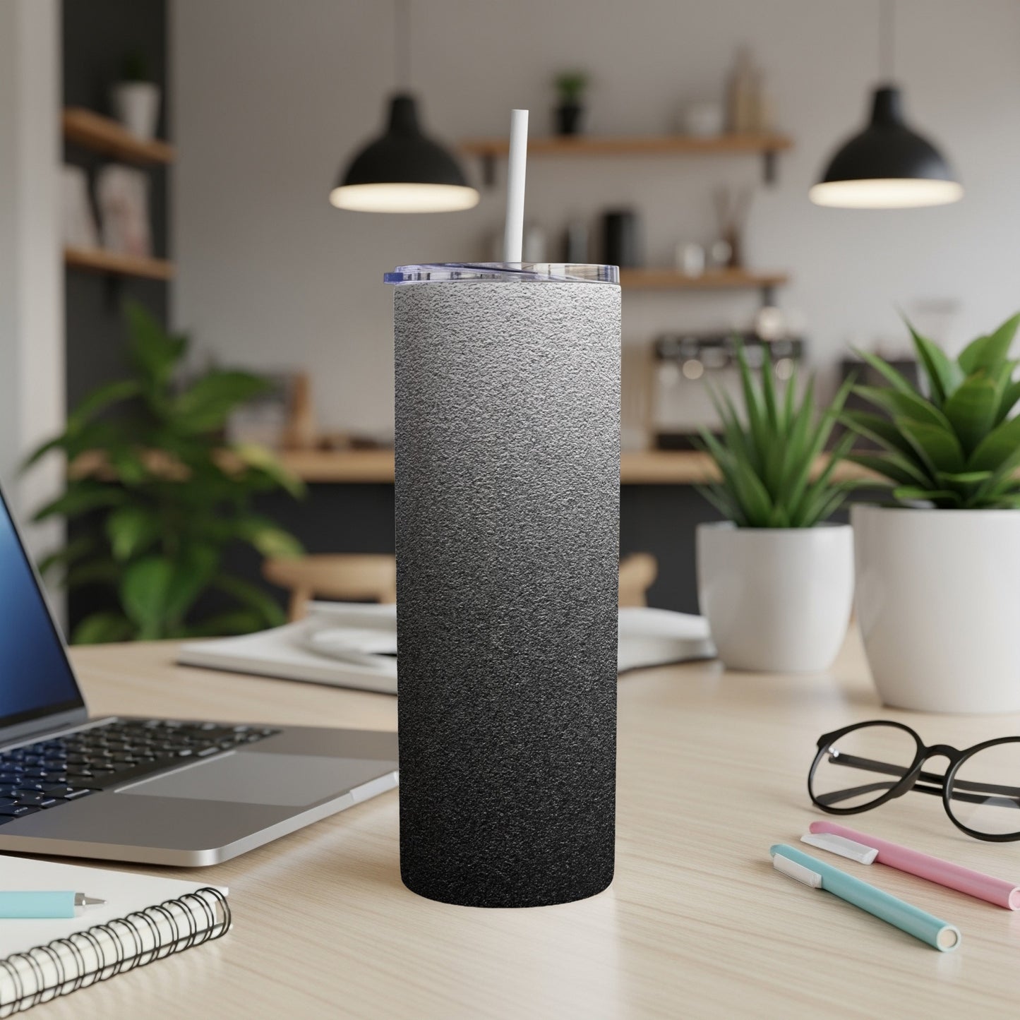 Black and white gradient tumbler with straw on a desk.