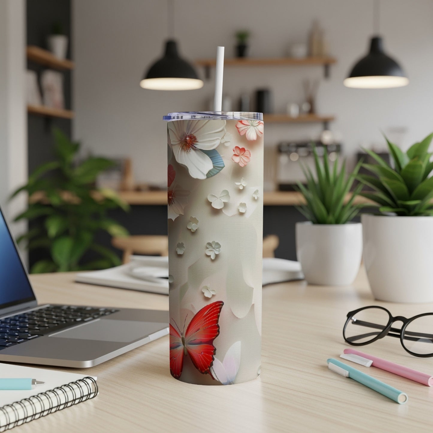 Tall tumbler with butterflies and floral design on a desk.