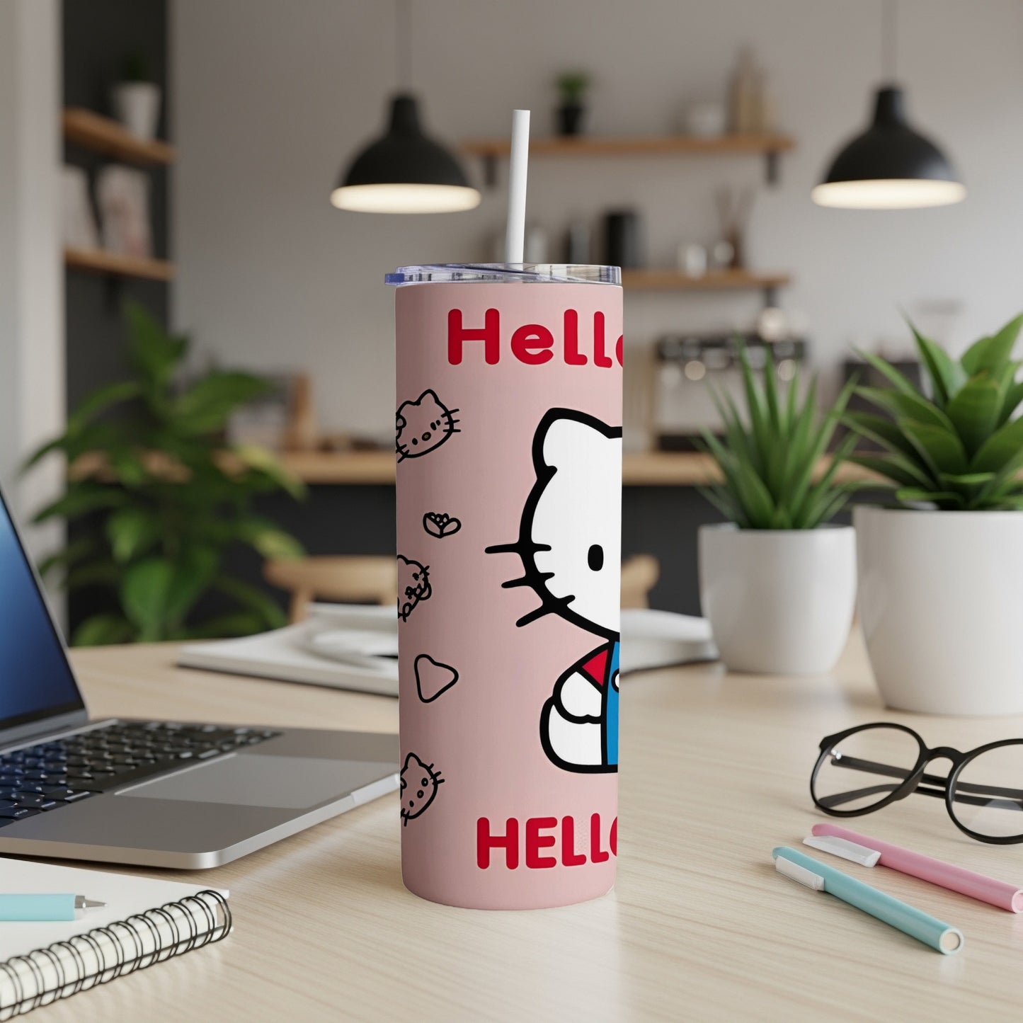 Pink Hello Kitty tumbler with straw on a desk with a laptop and pens.