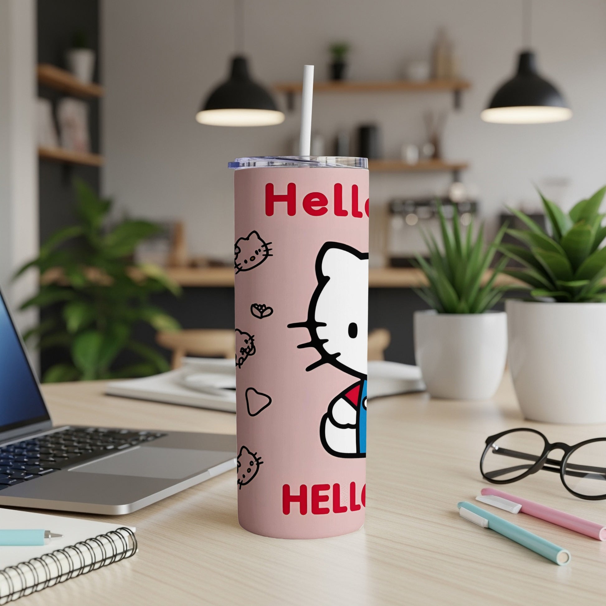 Pink Hello Kitty tumbler with straw on a desk with a laptop and pens.