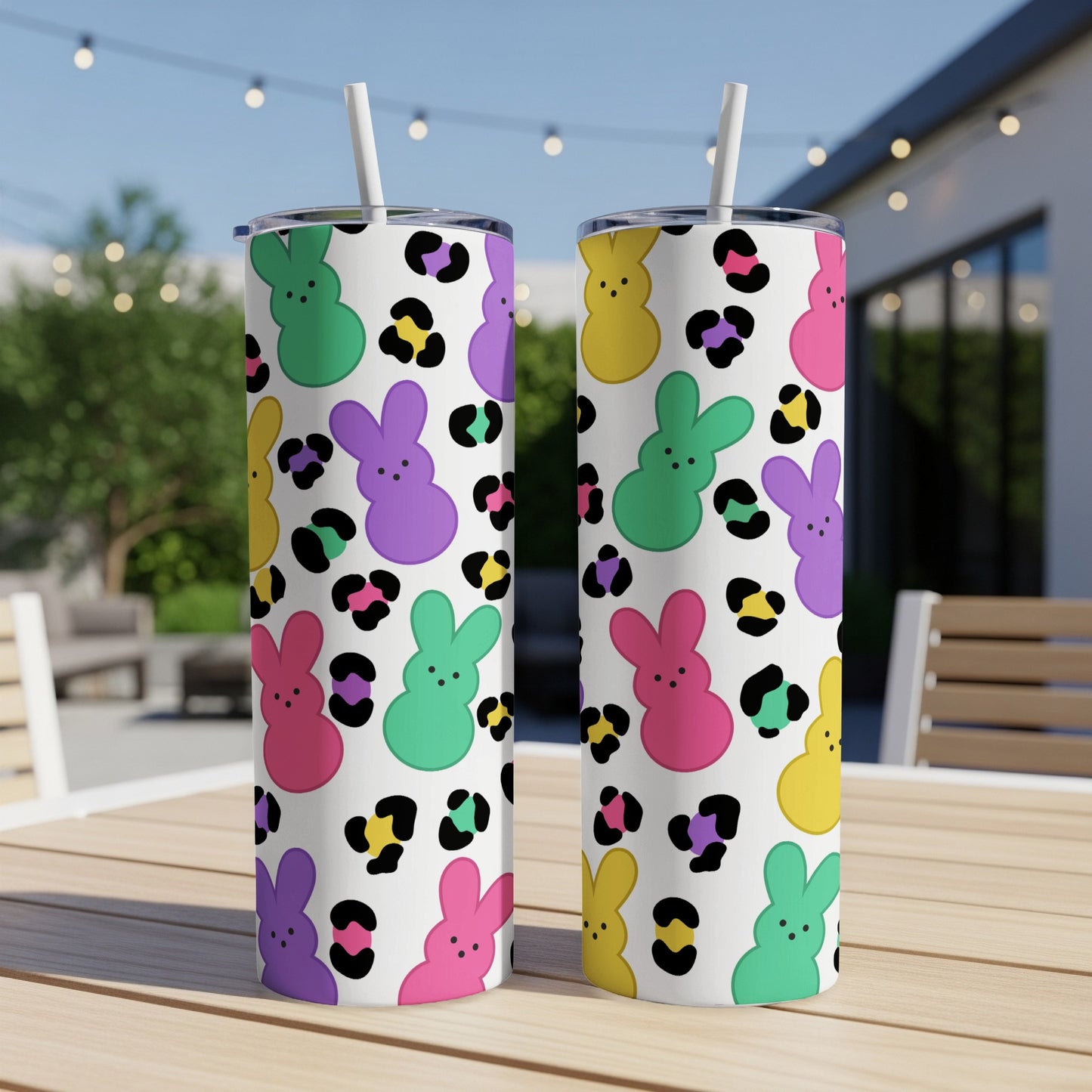 Two tumblers with colorful bunny and leopard print patterns on a table outdoors.