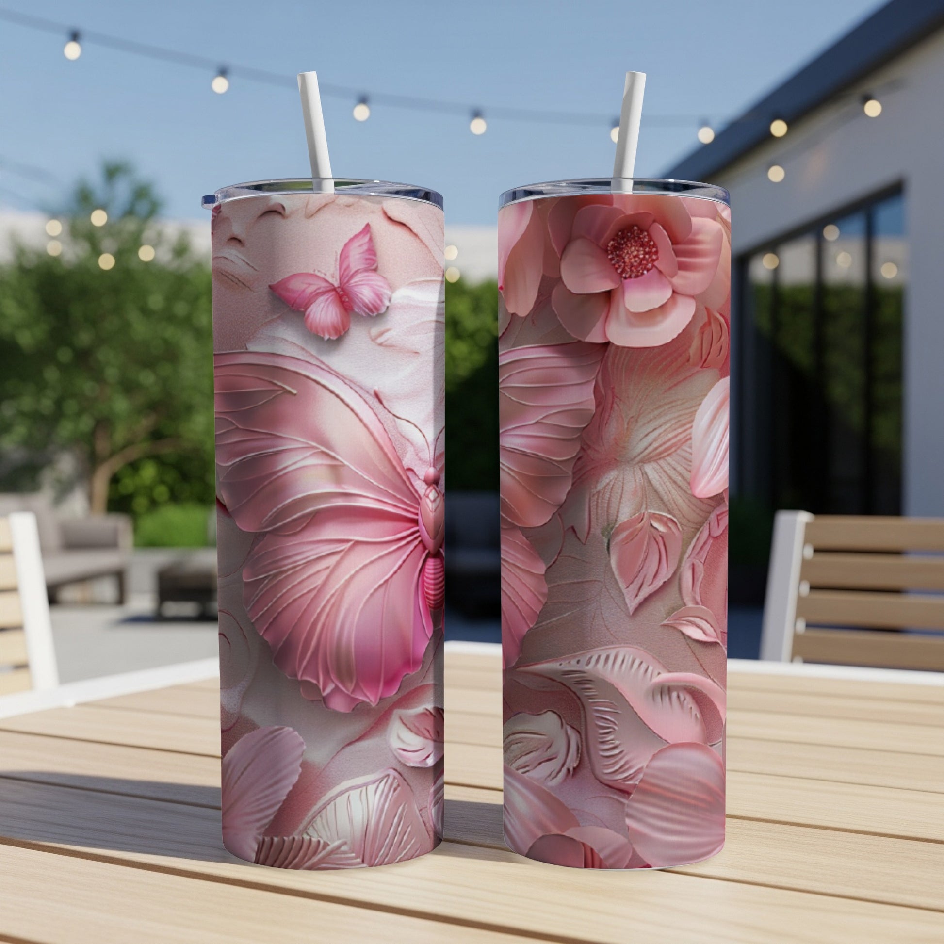 Two pink tumblers with embossed butterfly and floral designs on a table.