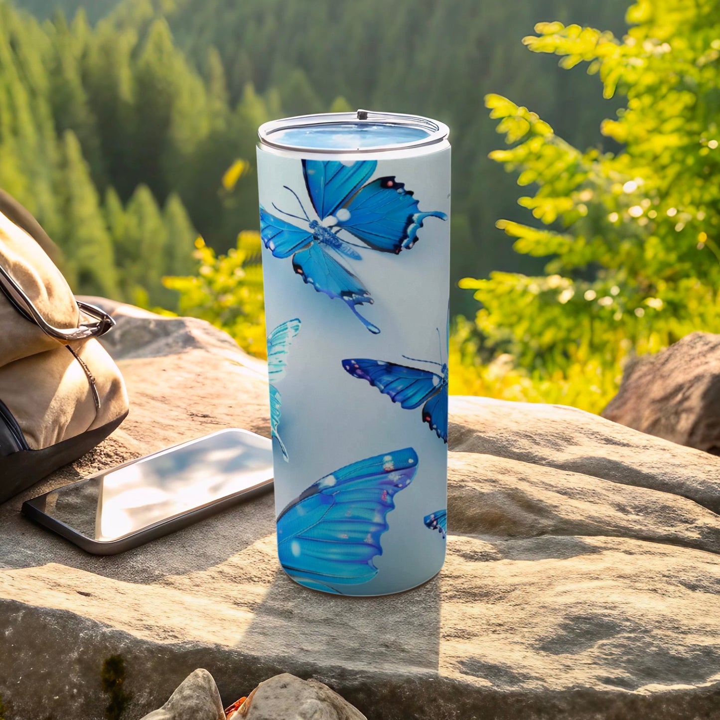 Blue butterfly design on a tall, slim tumbler with a phone and bag nearby.