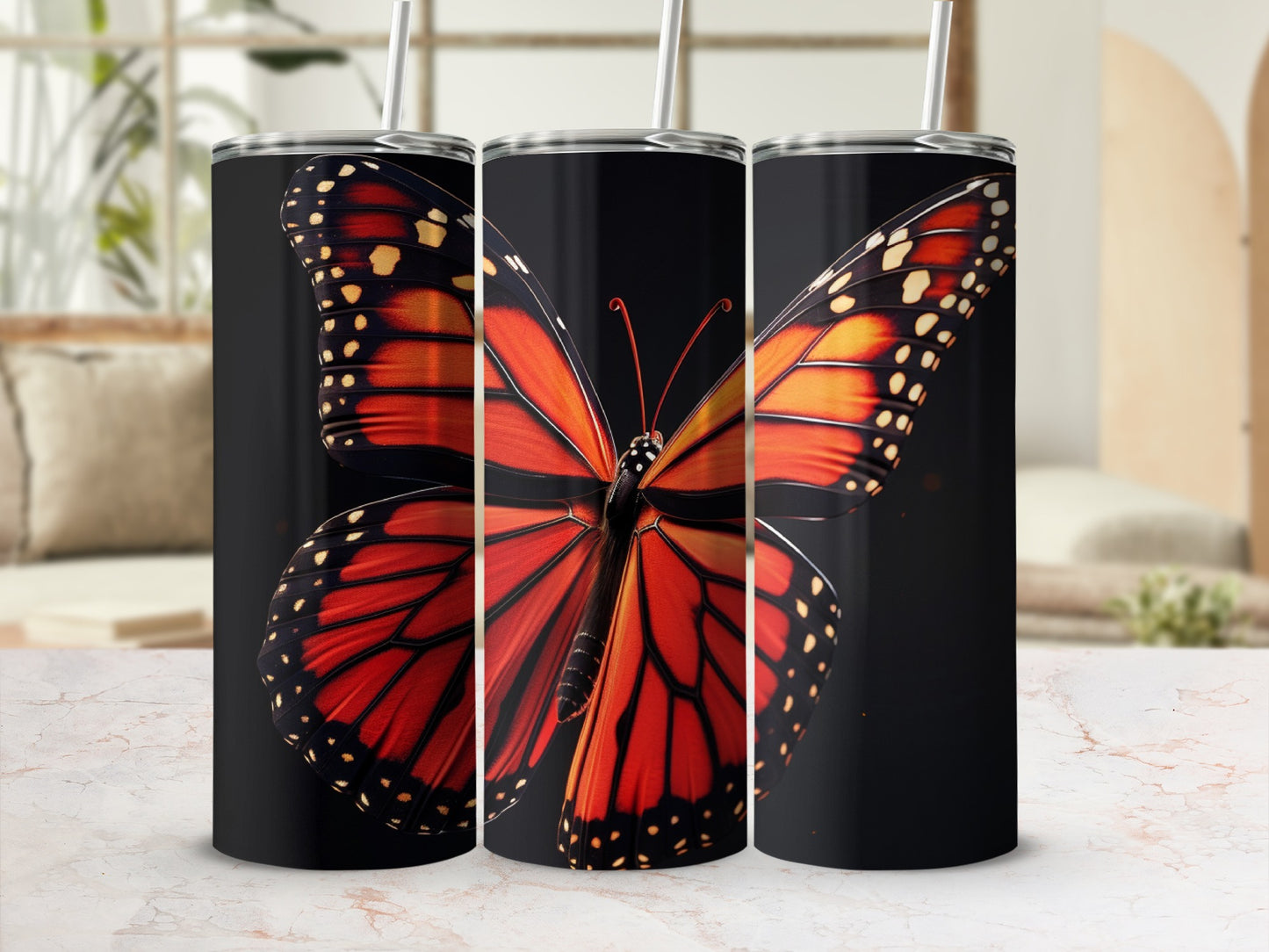 Monarch butterfly design on three black tumblers with straws.