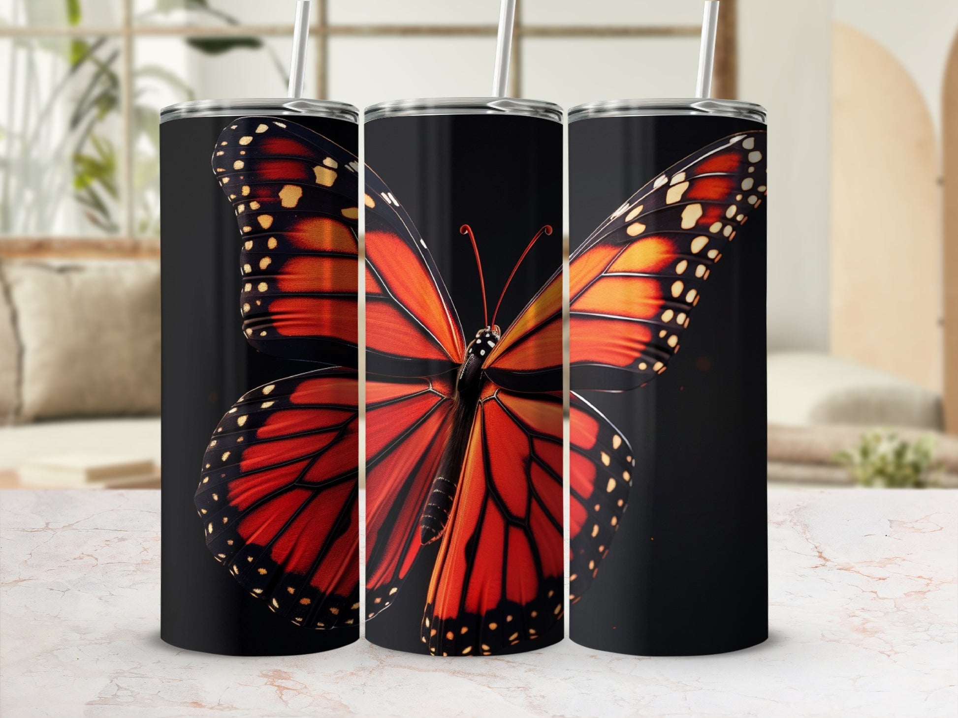 Monarch butterfly design on three black tumblers with straws.