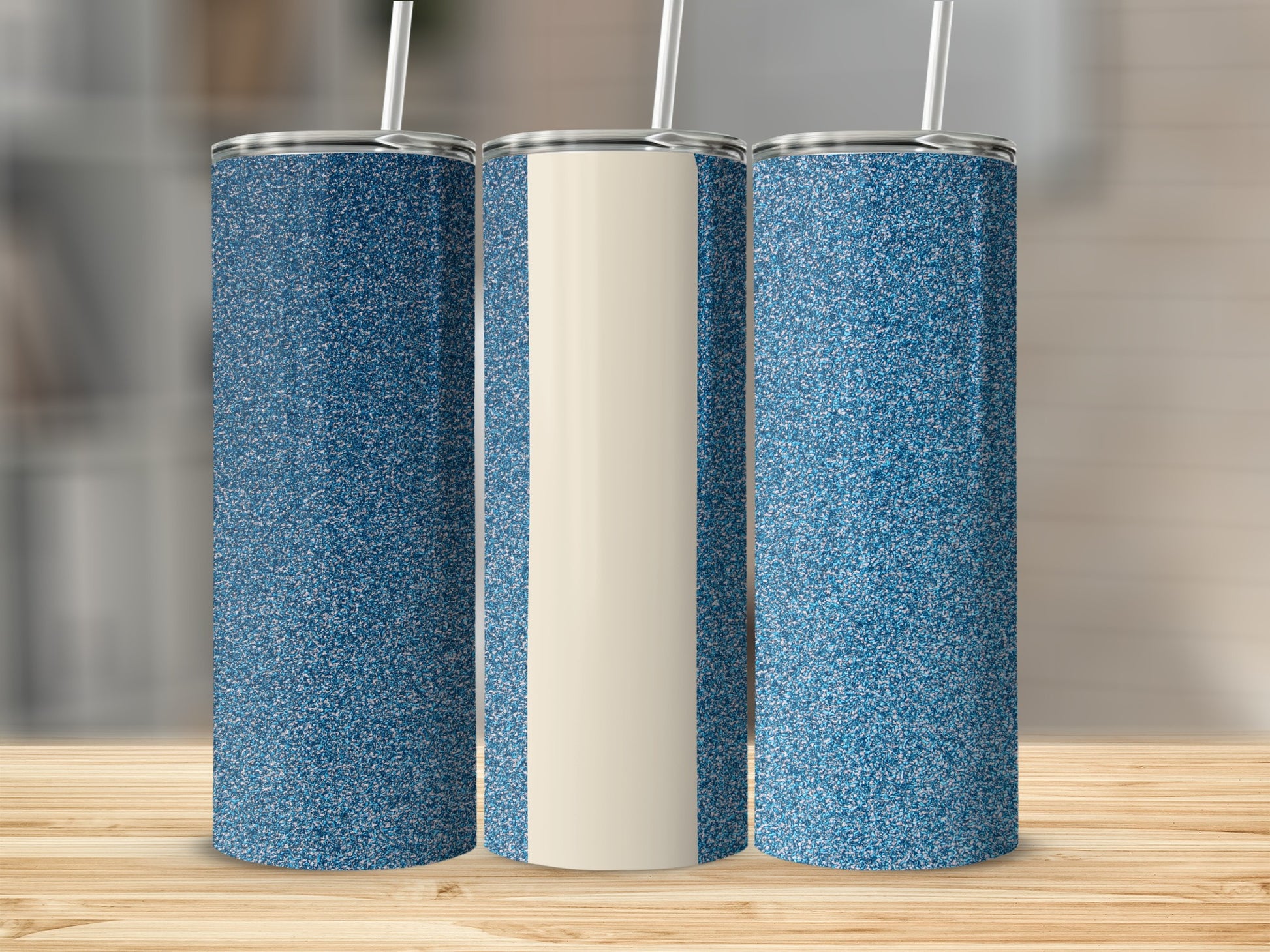 Three glitter-covered tumblers with straws on a wooden surface.