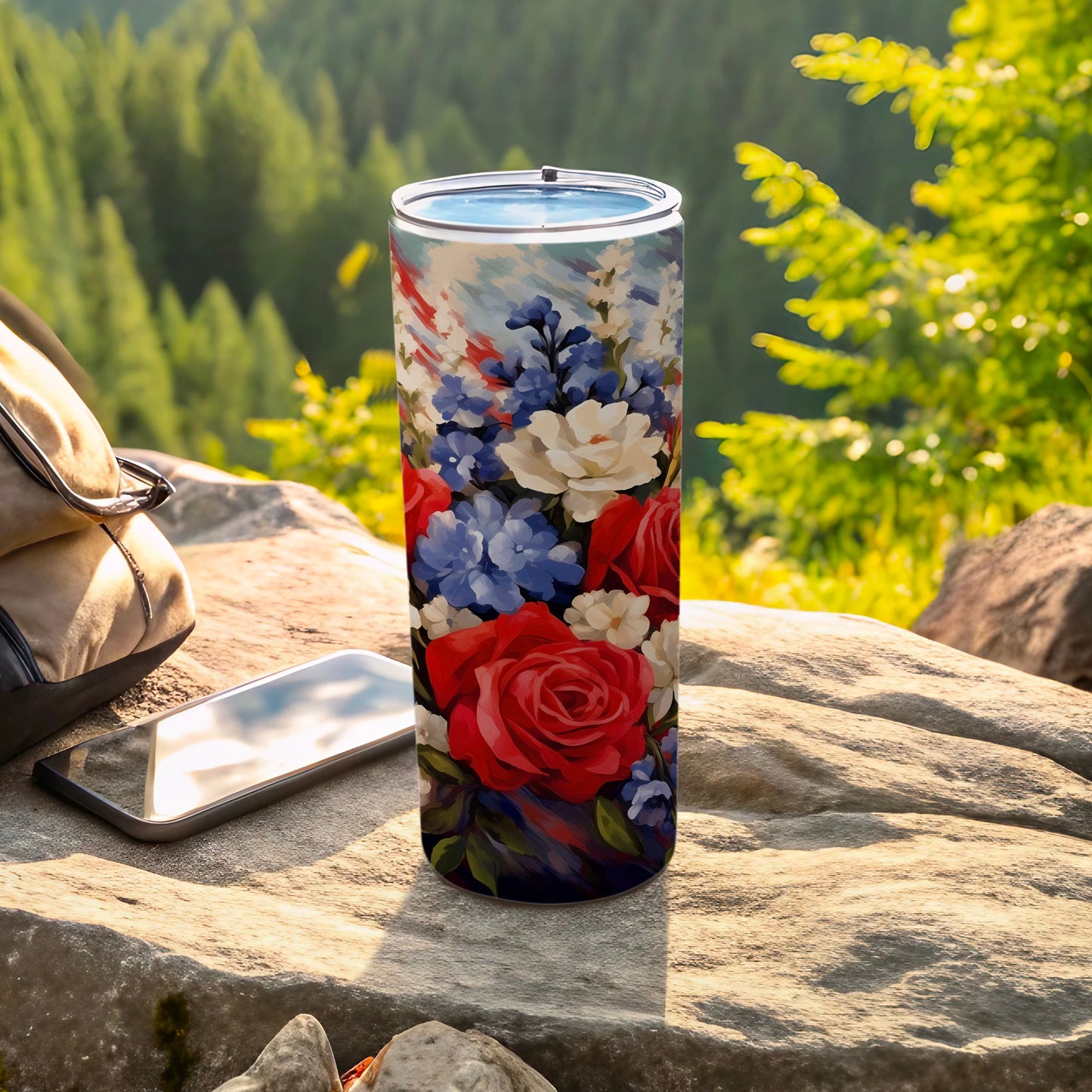 Floral-patterned tumbler on a rock, with a backpack and phone.