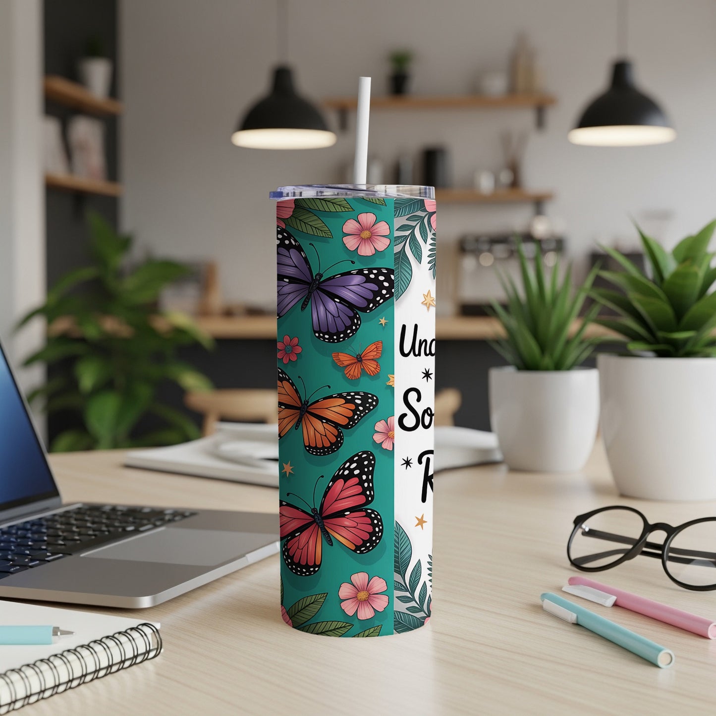 Tumbler with butterflies and floral print, white straw, sits on a desk.