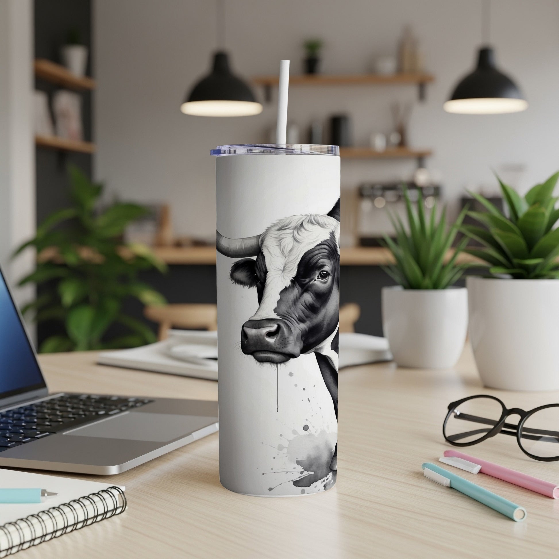 Black and white cow design on a white tumbler with a straw.