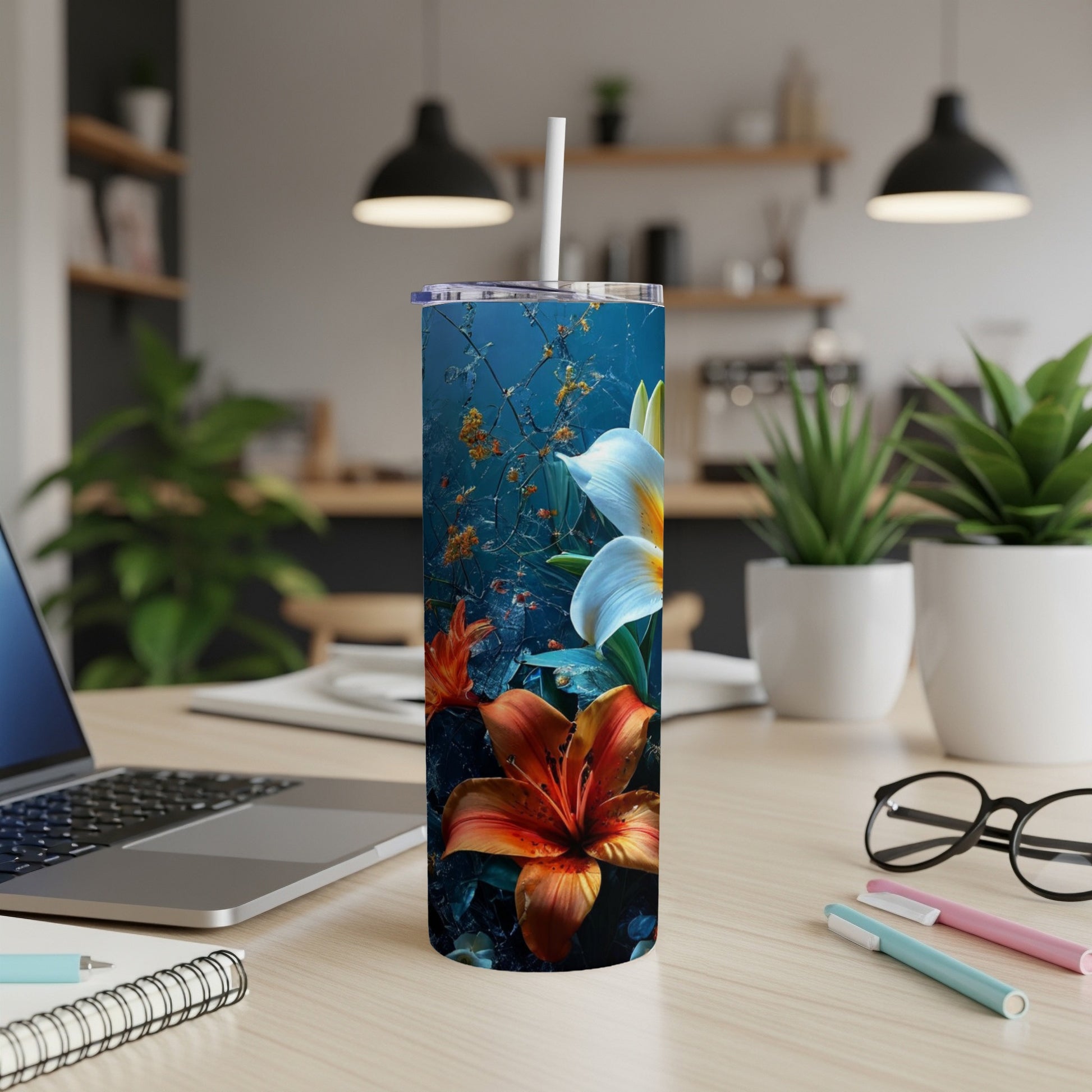 Tall tumbler with orange lily and white flower design on desk.