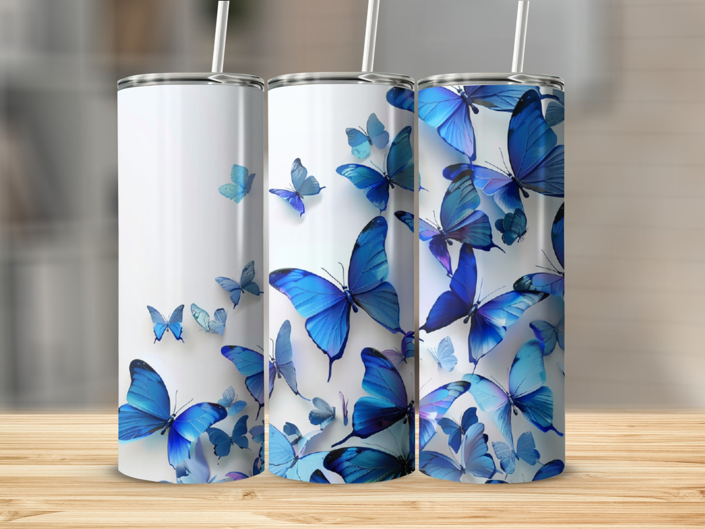 Three white tumblers with blue butterflies, displayed on a wooden surface.